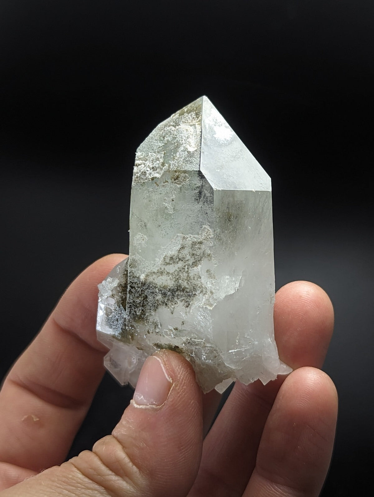 A translucent, clear quartz crystal with a pointed tip and natural inclusions.