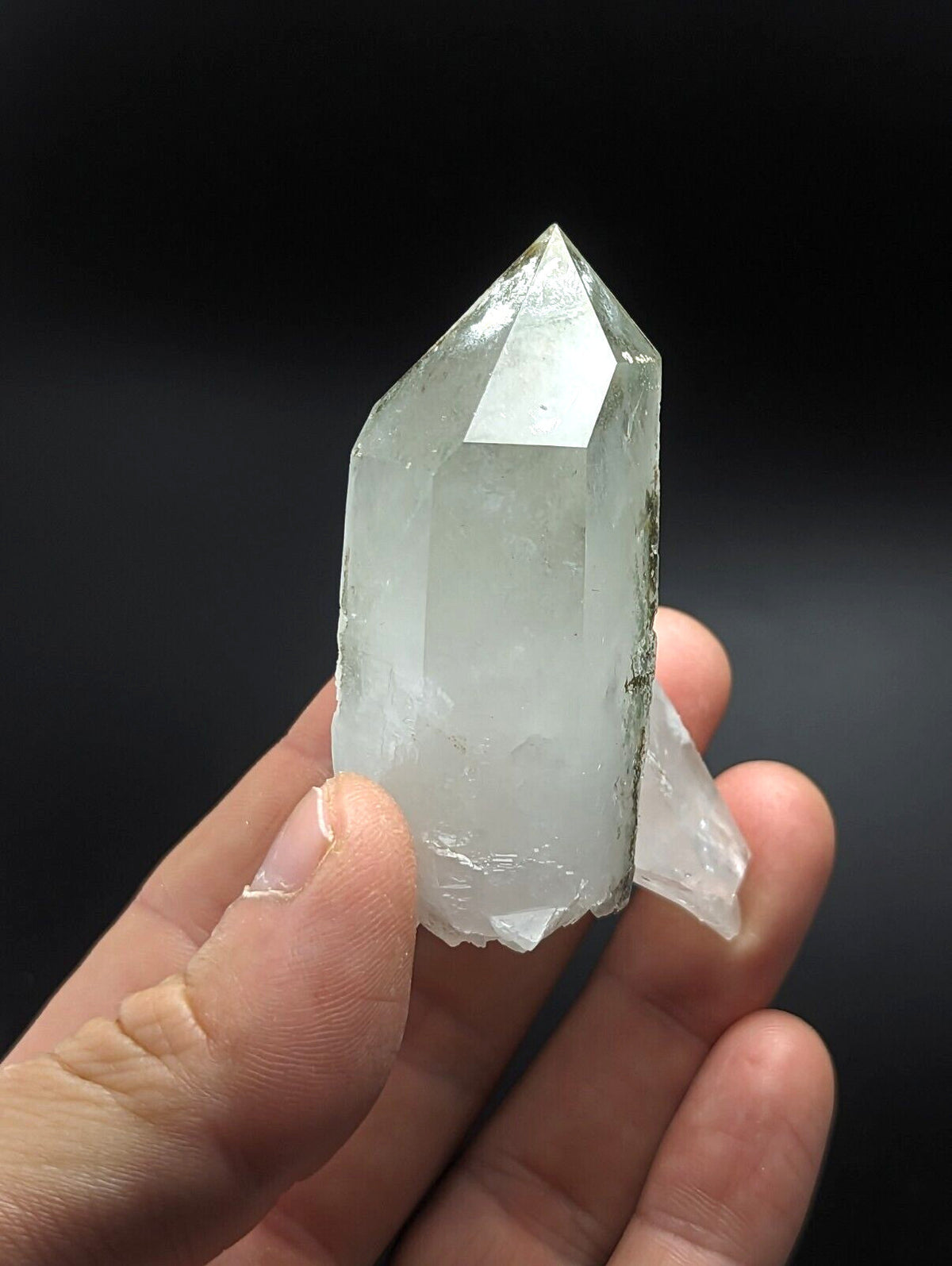 A translucent, clear quartz crystal with a pointed tip and natural facets.