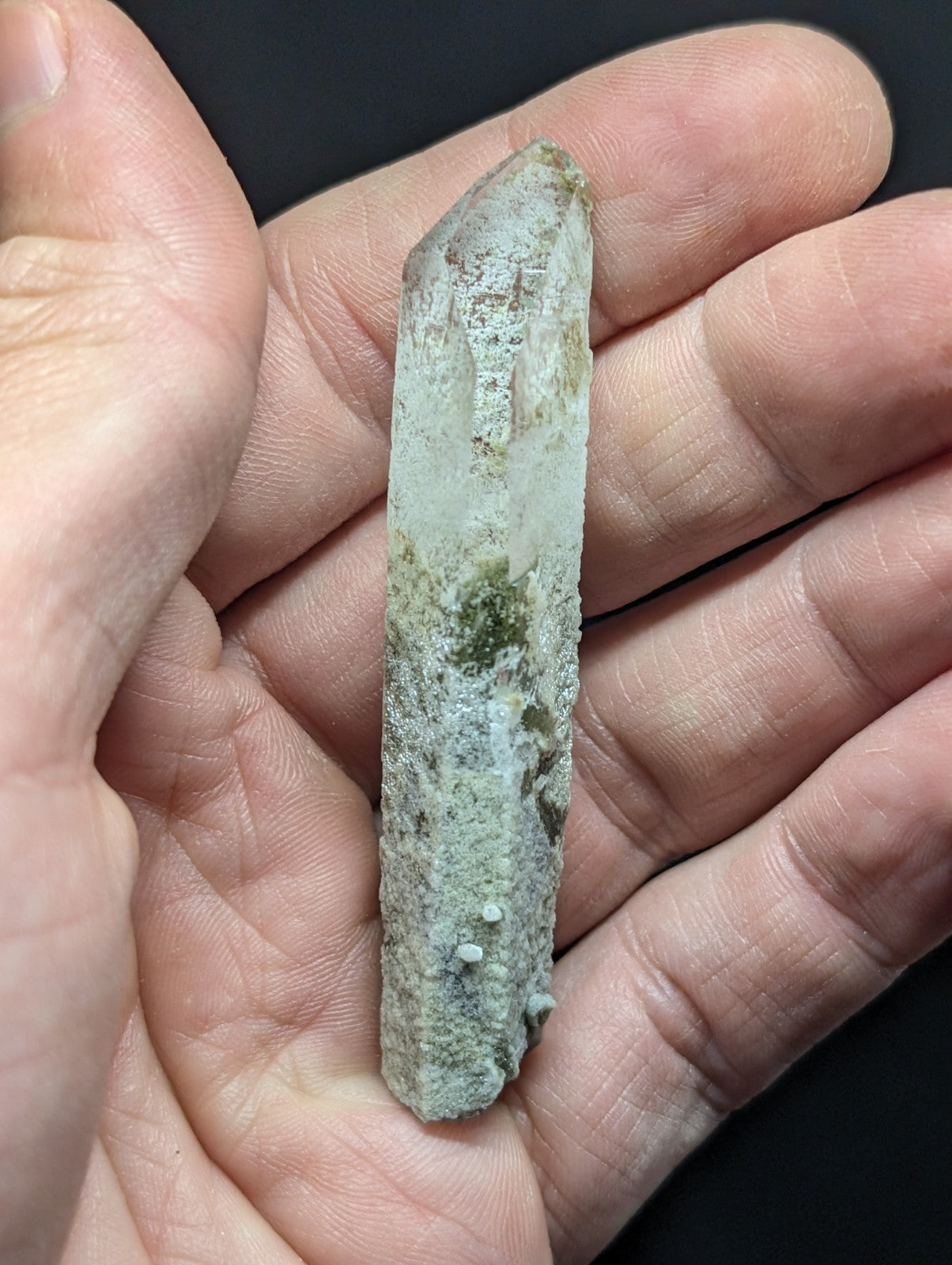 A translucent, pale green quartz crystal with natural mineral inclusions and a slightly rough, earthy texture.
