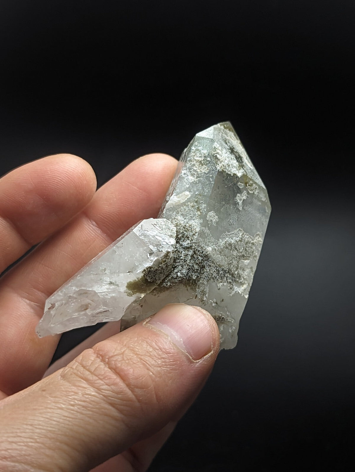 A translucent, pale green quartz crystal cluster with natural mineral inclusions and a pointed, faceted structure.