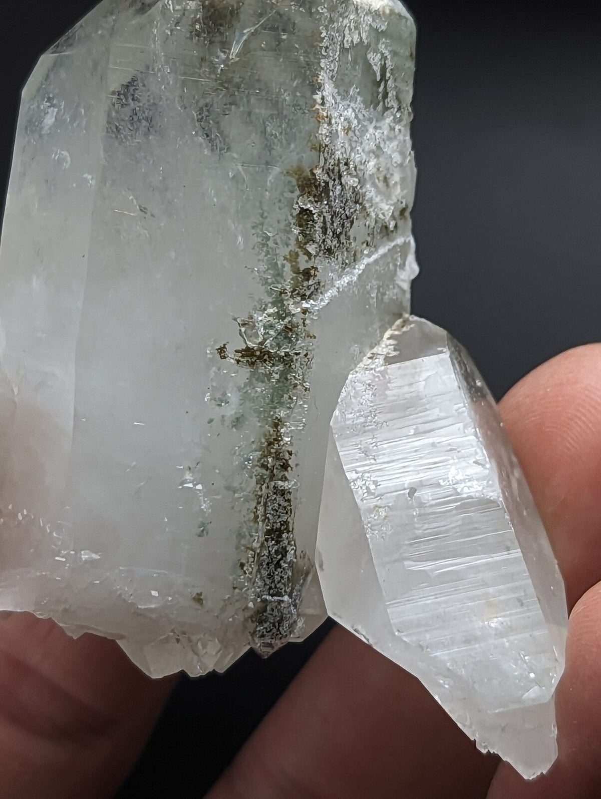 A translucent, clear quartz crystal cluster with a rough, jagged surface and subtle greenish mineral inclusions.