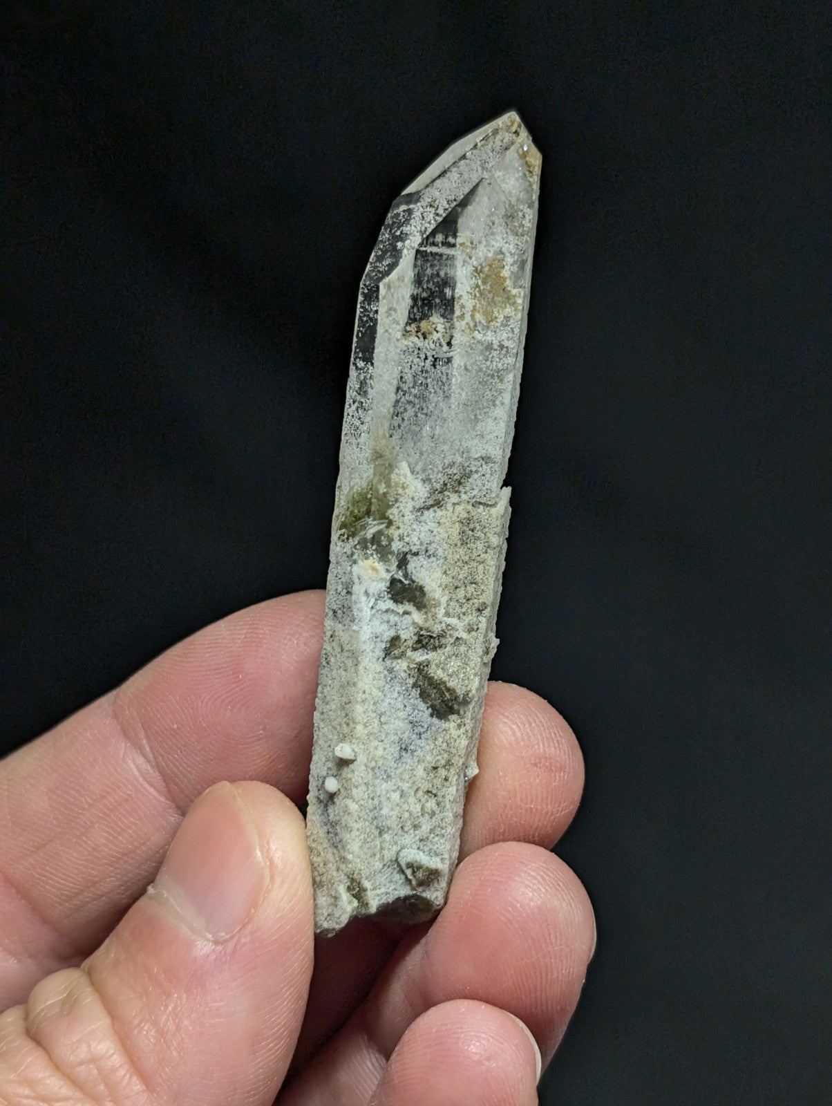 A translucent, pointed quartz crystal with a rough, earthy surface and subtle internal inclusions.