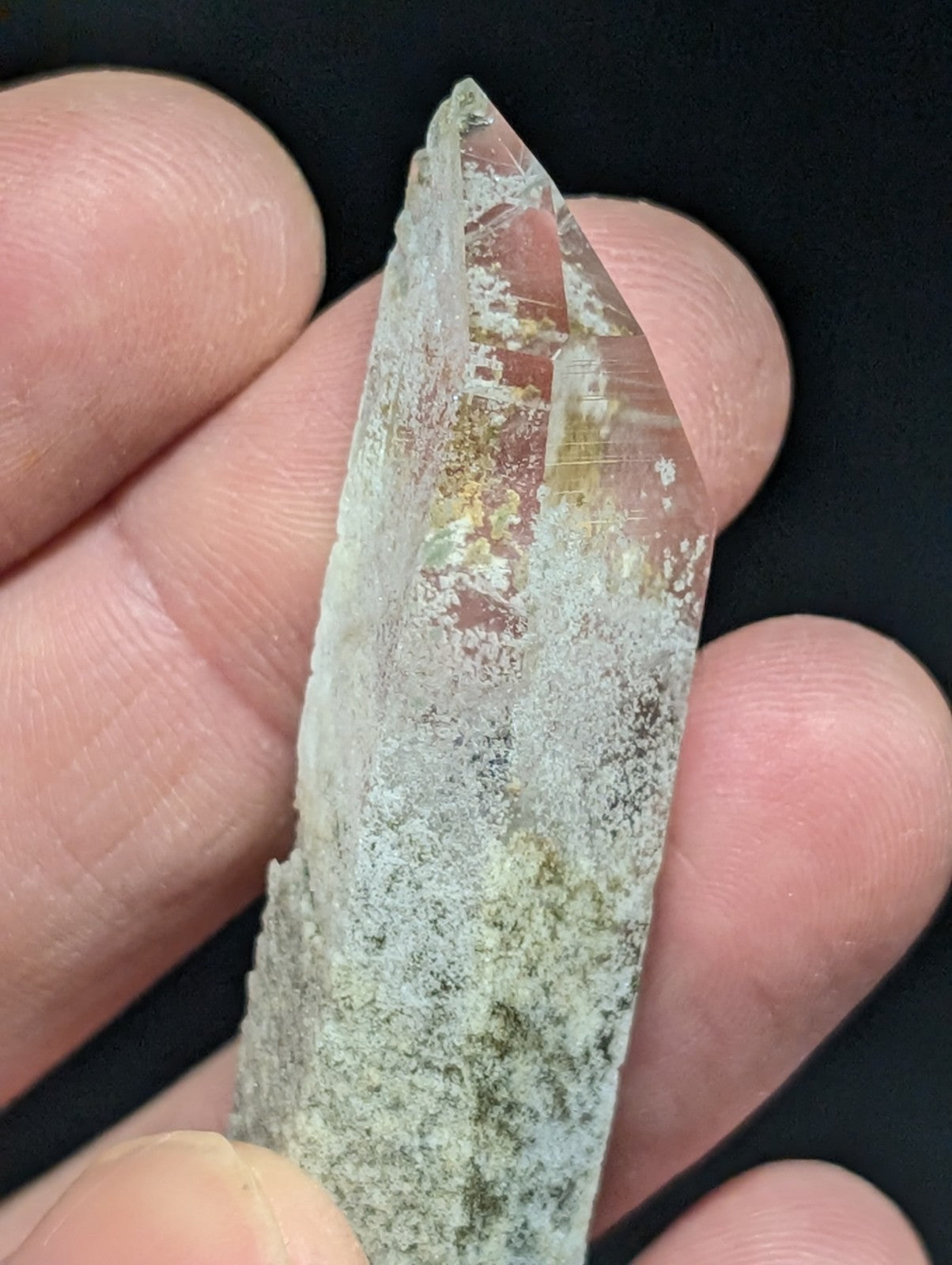A translucent quartz crystal with a pointed tip, featuring natural inclusions and a slightly cloudy base.