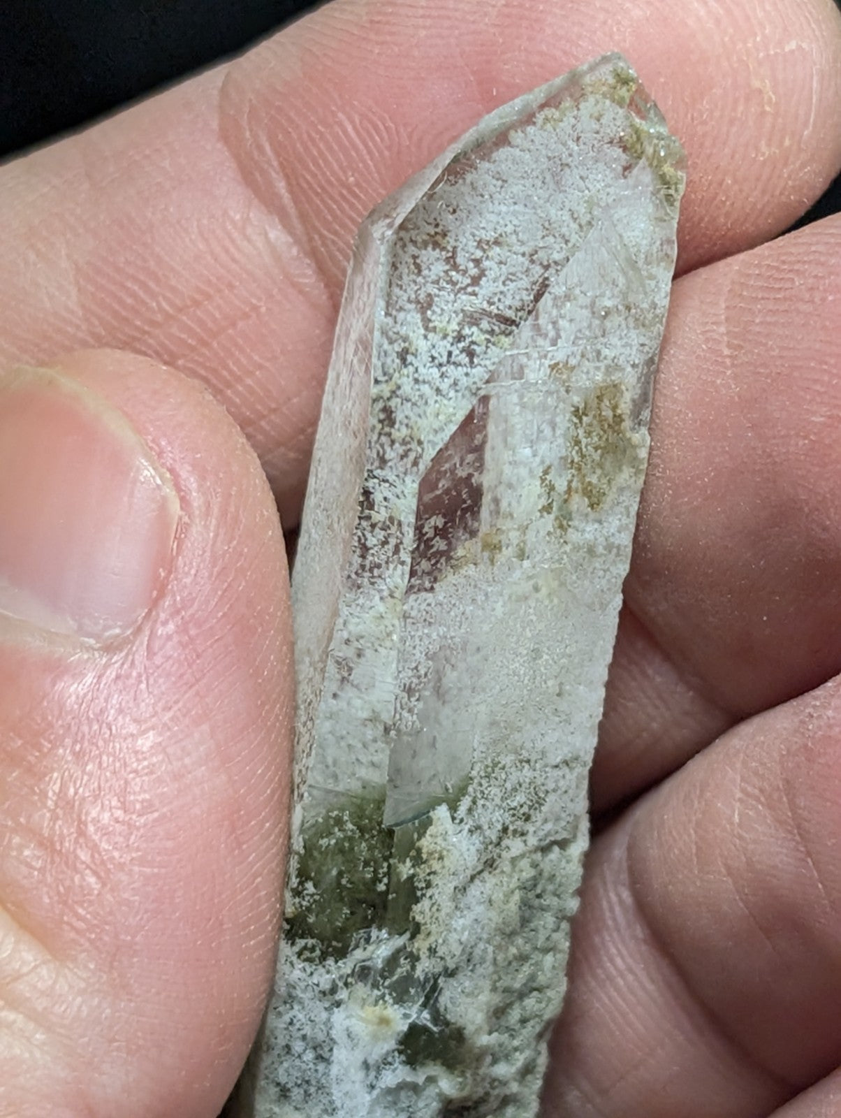 A translucent, pale green quartz crystal with natural inclusions and a rough, earthy base.