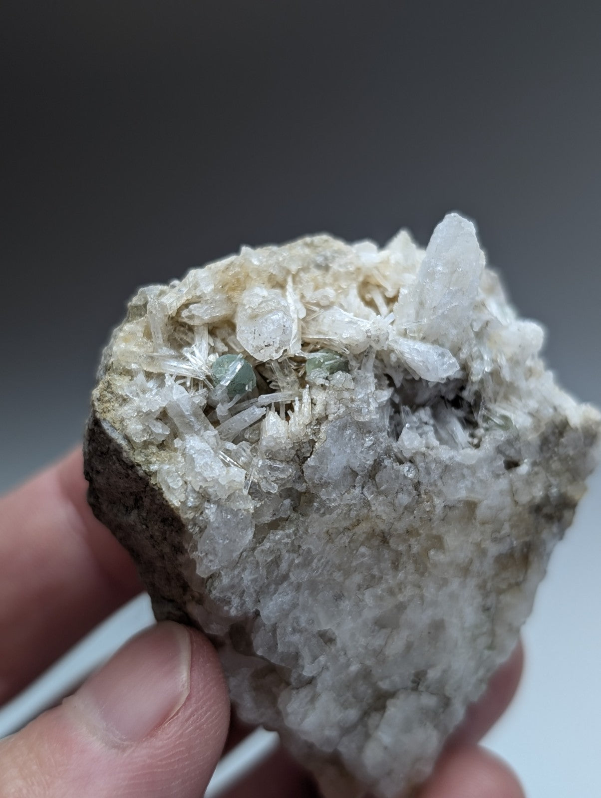 A hand holds a rare green cookeite on solution quartz mineral with pale green crystals from saline county Arkansas