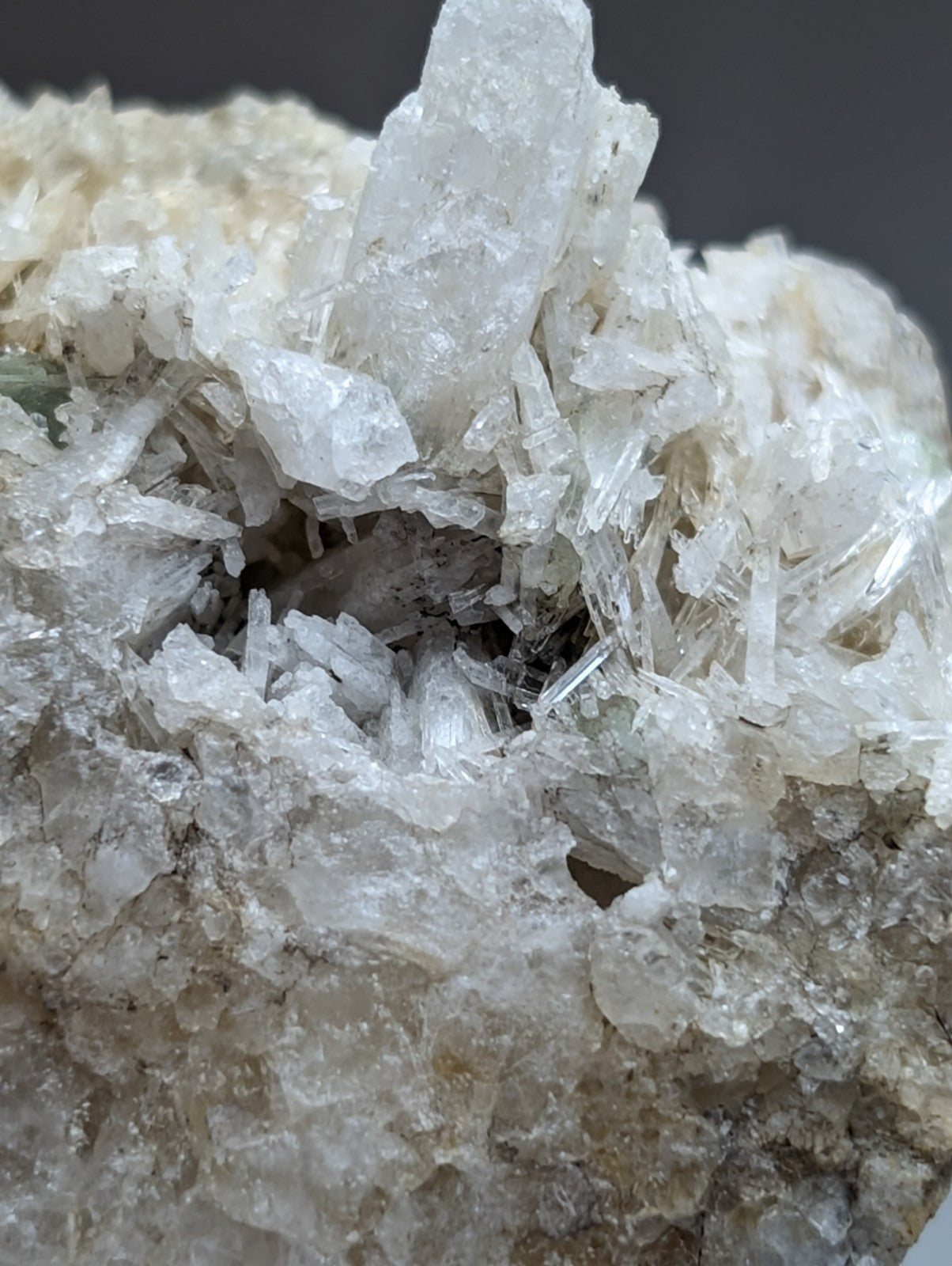 A cluster of translucent quartz crystals with sharp edges in clear and milky white hues on green cookeite matrix