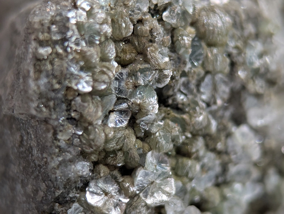 A cluster of translucent, faceted crystals with a grayish hue and metallic sheen.