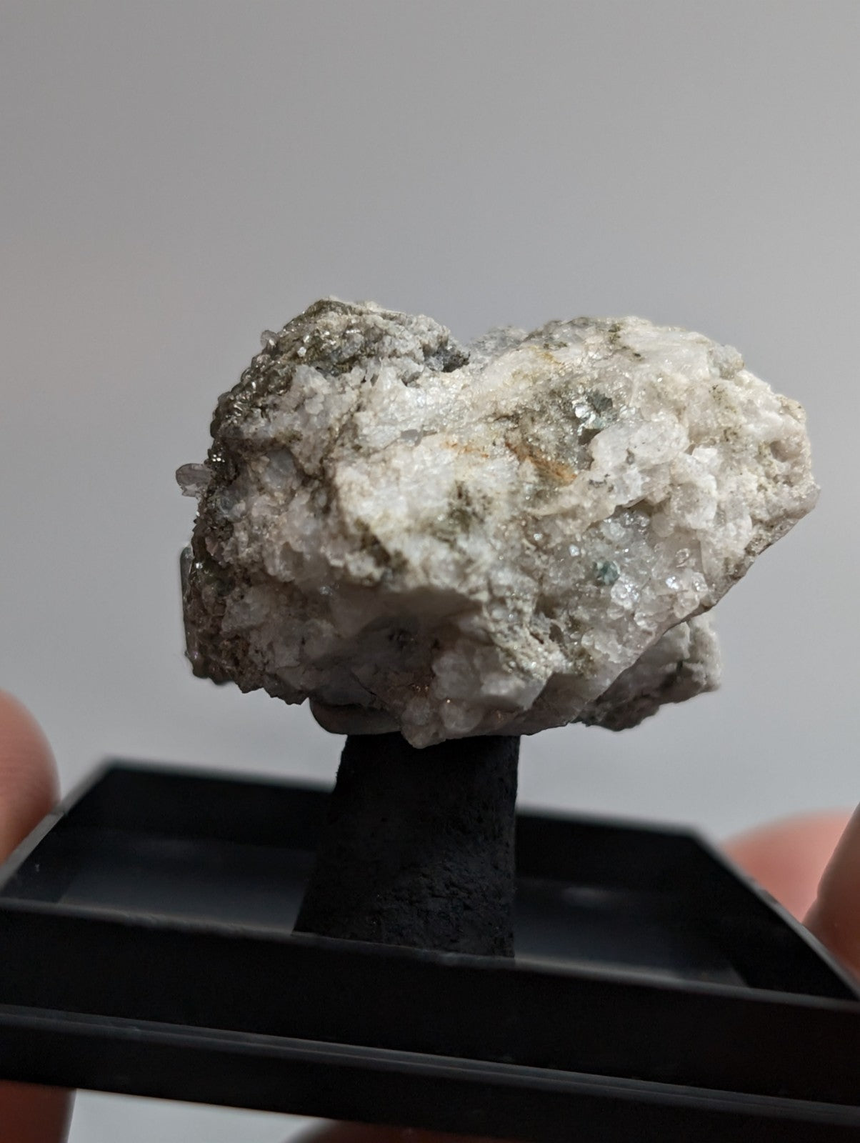 A textured, irregularly shaped mineral specimen with a mix of white and gray crystalline formations.