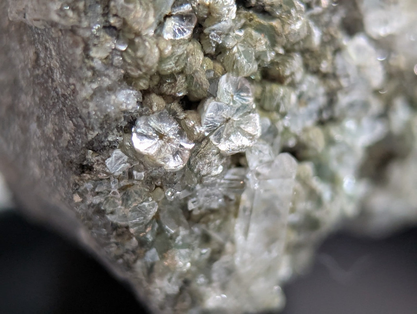 Clear, faceted quartz crystals cluster together on a grayish rock matrix.