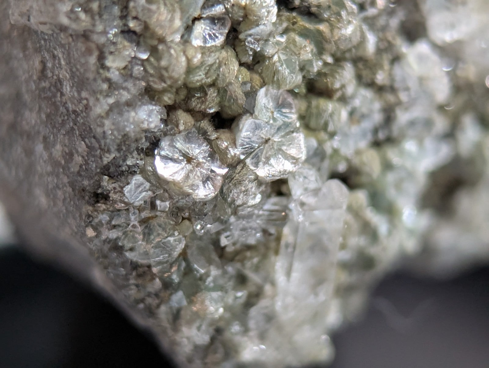 Clear, faceted quartz crystals cluster together on a grayish rock matrix.