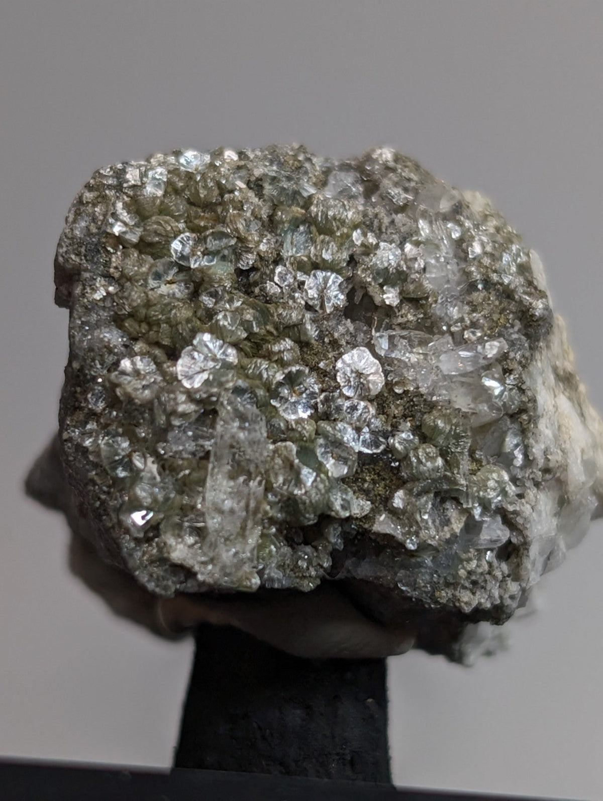 A rough, irregularly shaped mineral specimen featuring a dense cluster of clear, faceted crystals growing from a darker, earthy matrix.