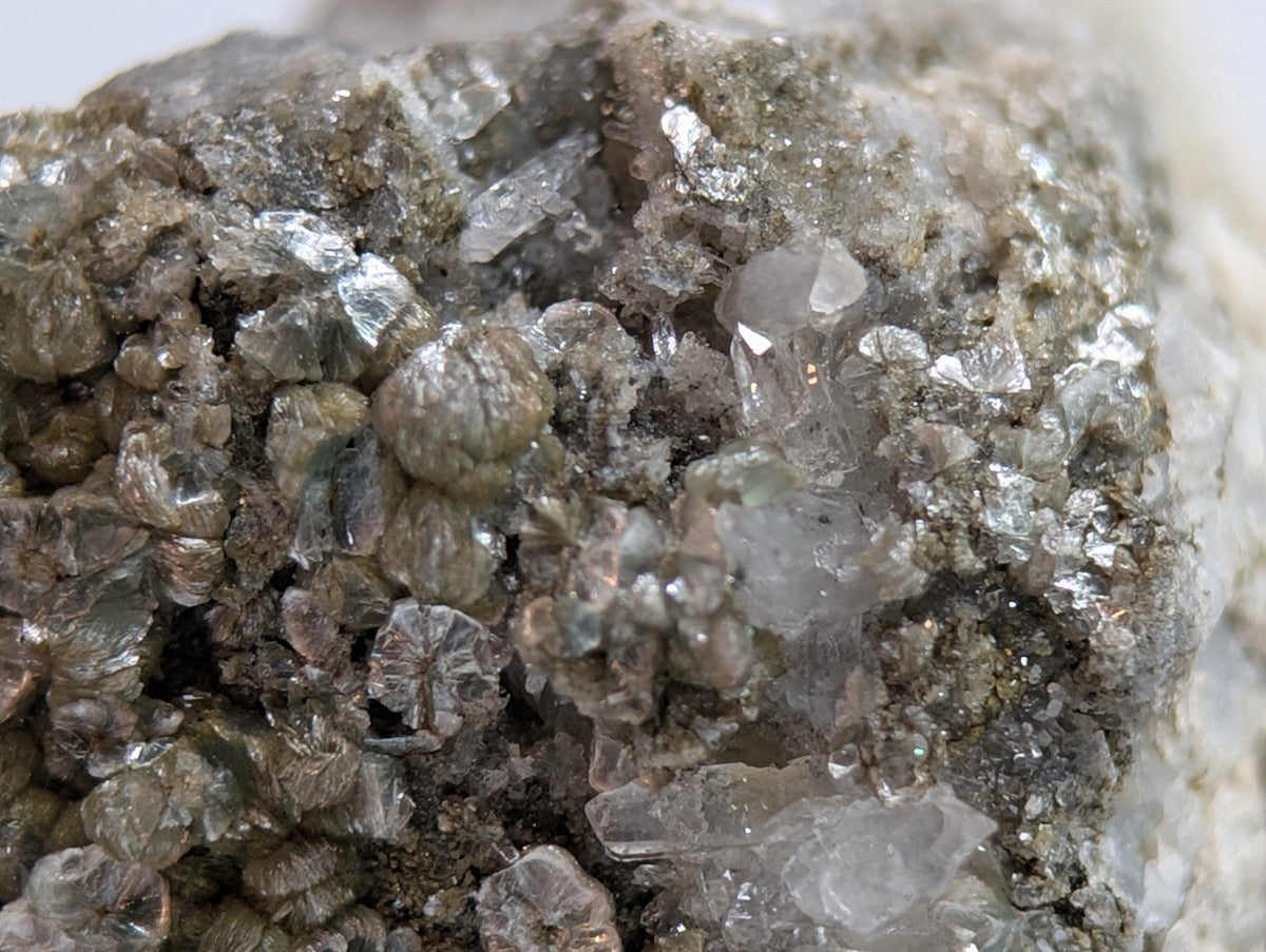 A cluster of translucent, grayish crystals with a rough, earthy matrix.
