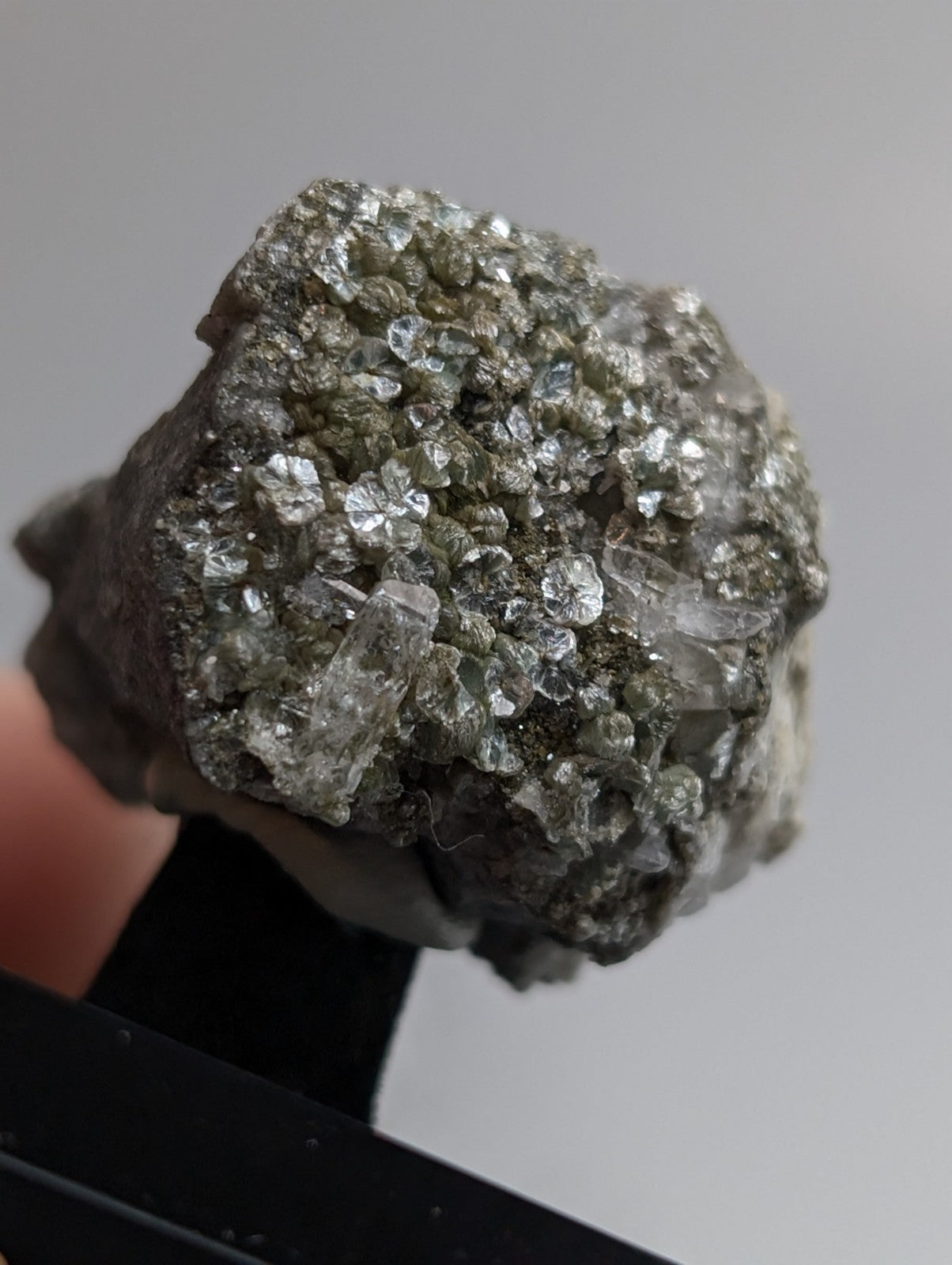 A rough, irregularly shaped mineral specimen featuring a dense cluster of translucent, clear to pale green crystals growing from a darker gray matrix.