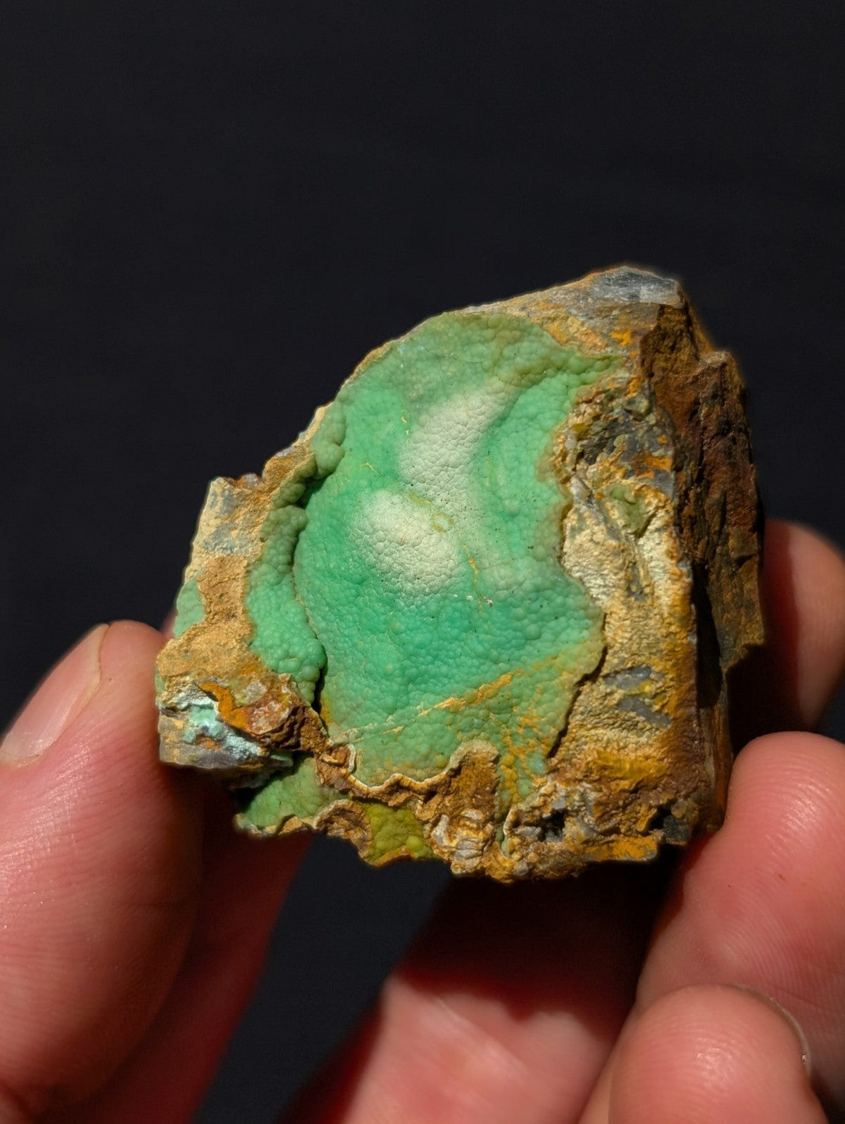 A rough, irregularly shaped piece of turquoise mineral with a vibrant green center and earthy brownish-yellow outer matrix.
