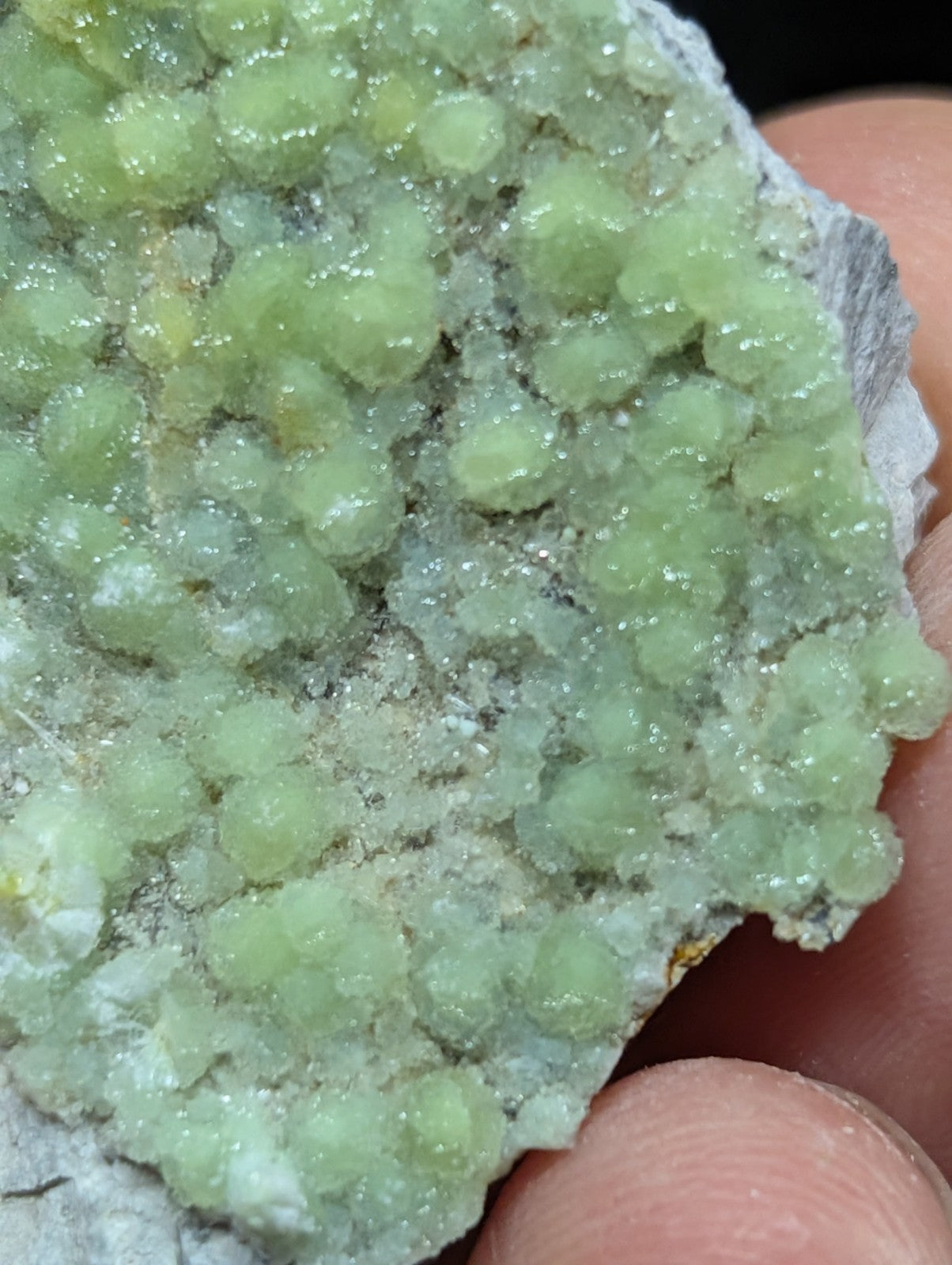 A cluster of translucent, light green crystals with a crystalline texture and slightly glossy surface.