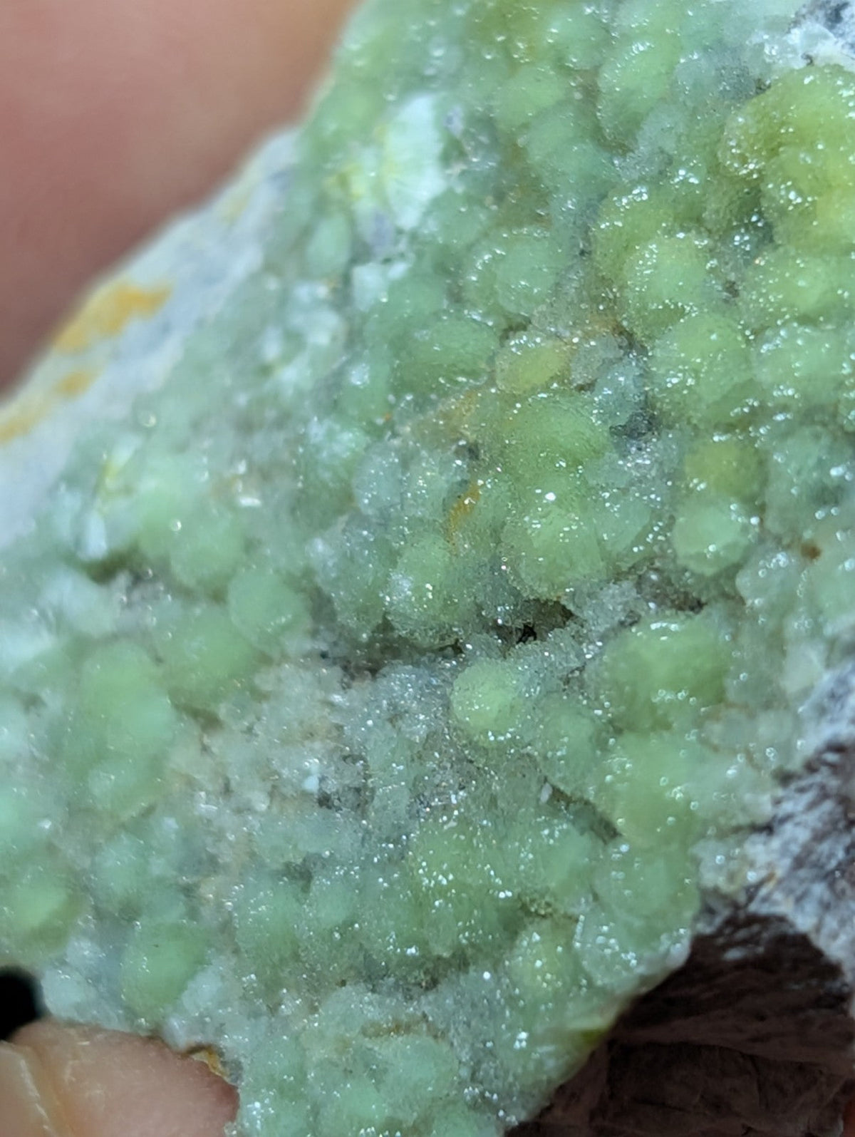 A cluster of translucent, light green crystals with a sparkling, crystalline texture.