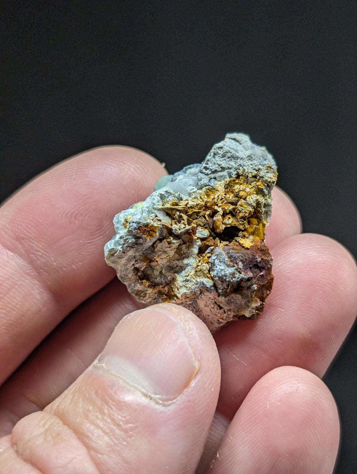A rugged, irregularly shaped mineral specimen with a mix of grayish-blue and golden-yellow hues.