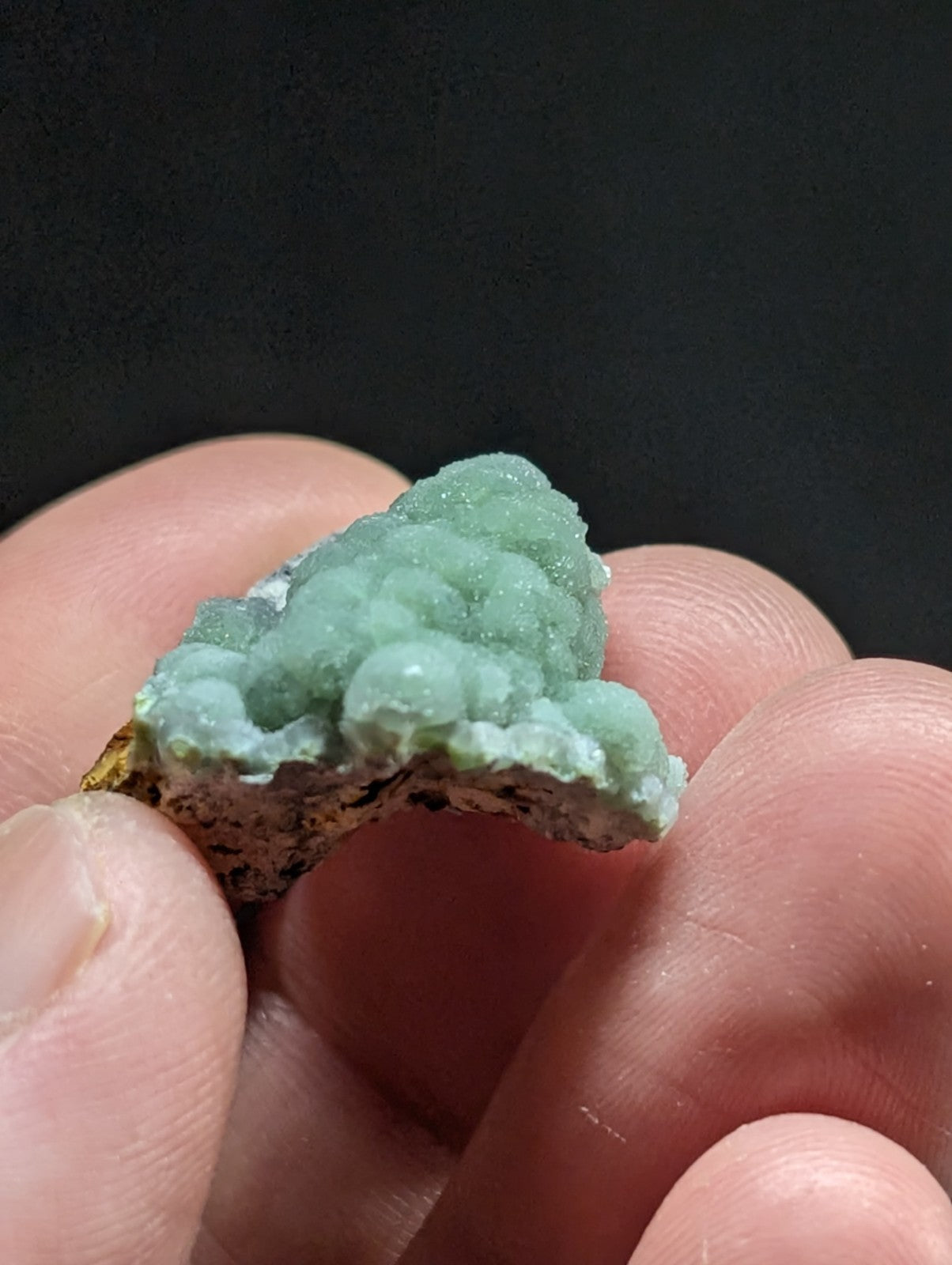 A delicate, light green mineral specimen with a clustered, bubble-like formation and rough-textured base.