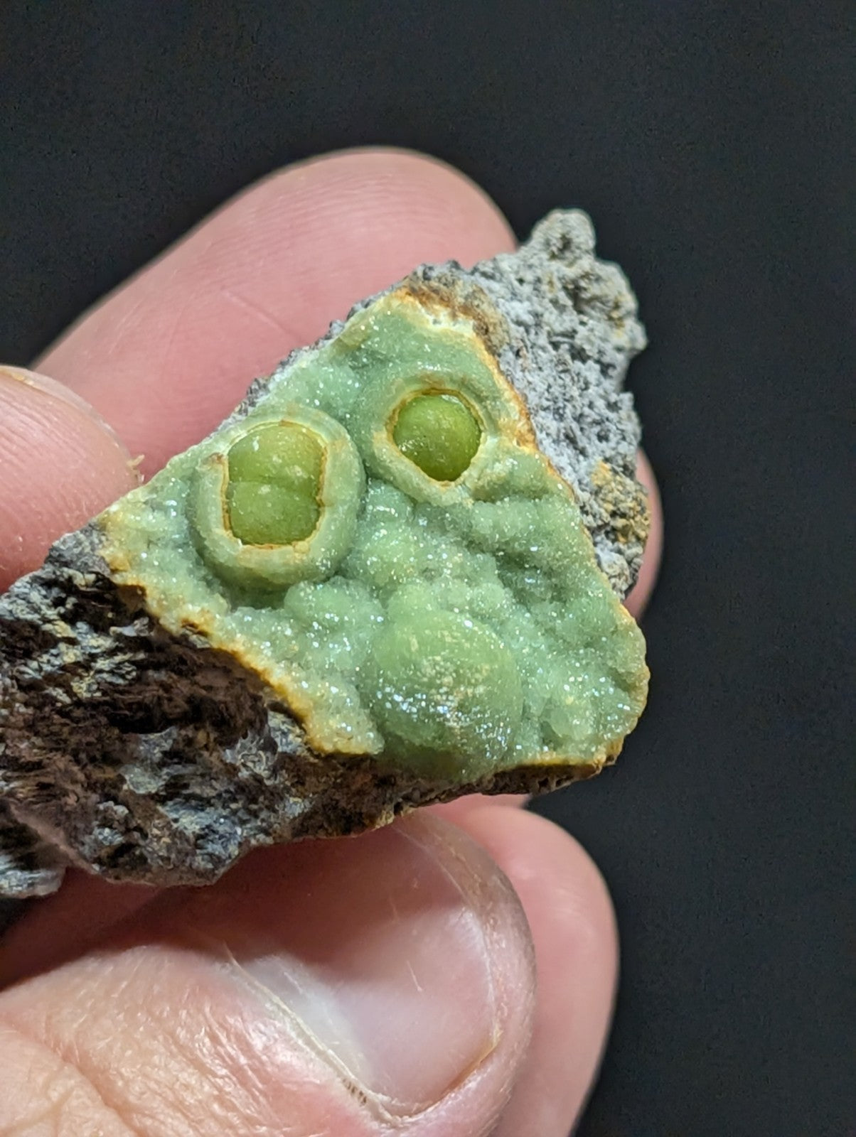A green, textured mineral specimen with two prominent circular inclusions resembling eyes.