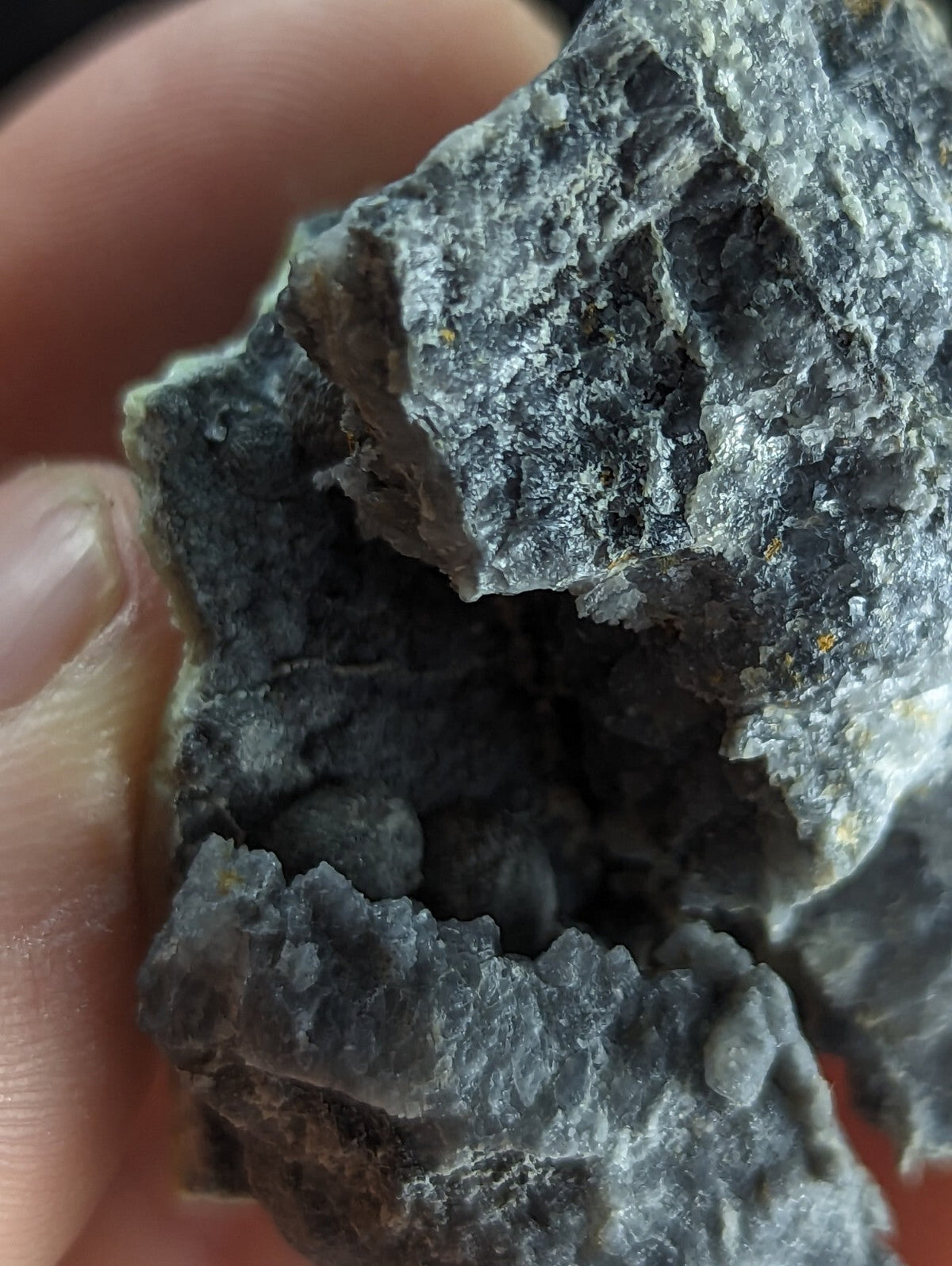 A rough, dark gray rock with a jagged surface and visible internal crystalline structure.
