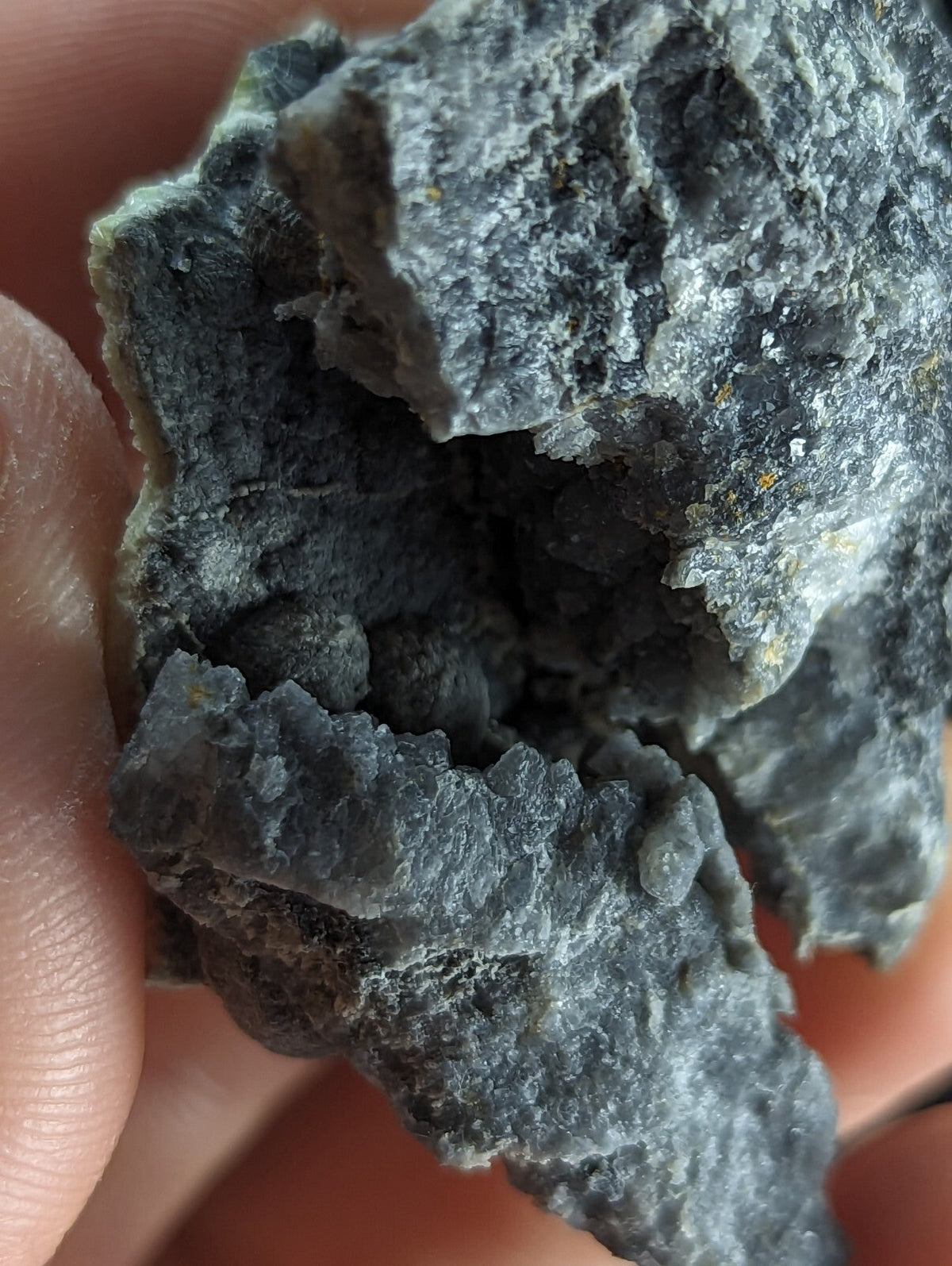 A rough, dark gray rock with a textured surface and visible crystalline formations.