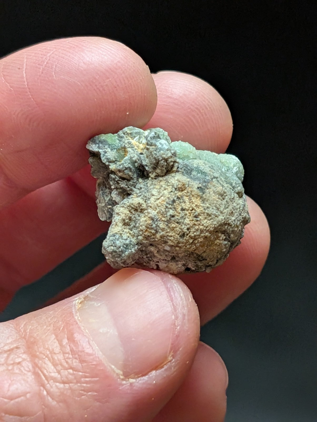 A rough, irregularly shaped mineral specimen with a mottled green and beige surface.