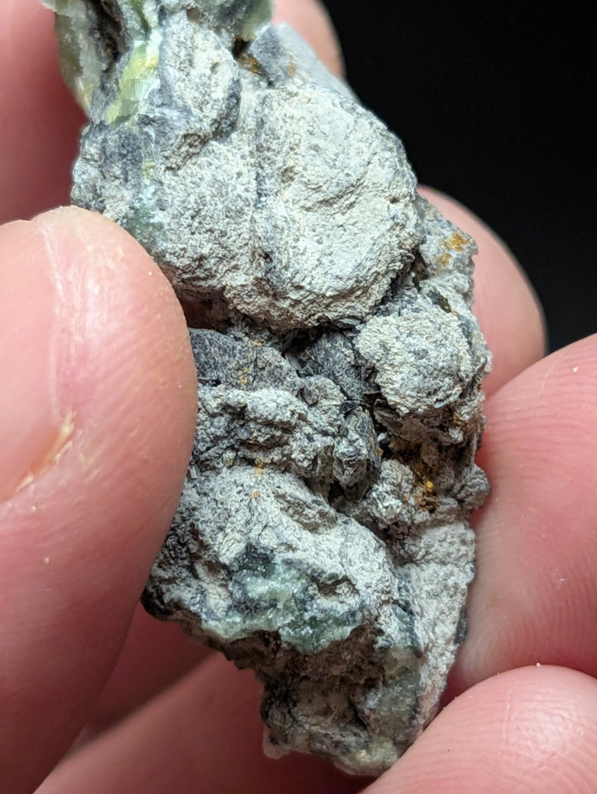 A rough, irregularly shaped mineral specimen with a mottled gray and green surface.