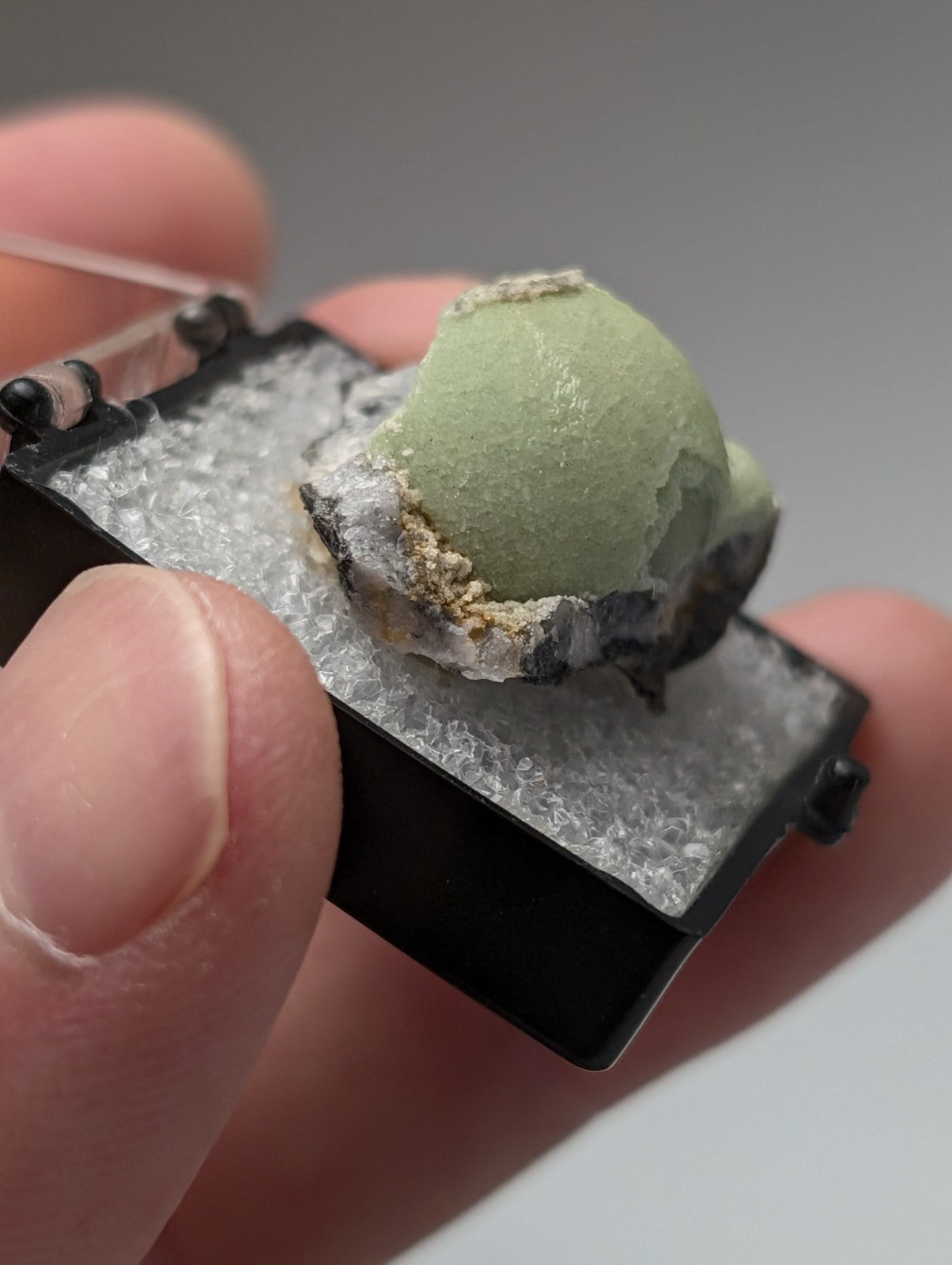 A miniature black plastic ice cream truck model with white textured interior holding mint green scoop of Green Wavellite