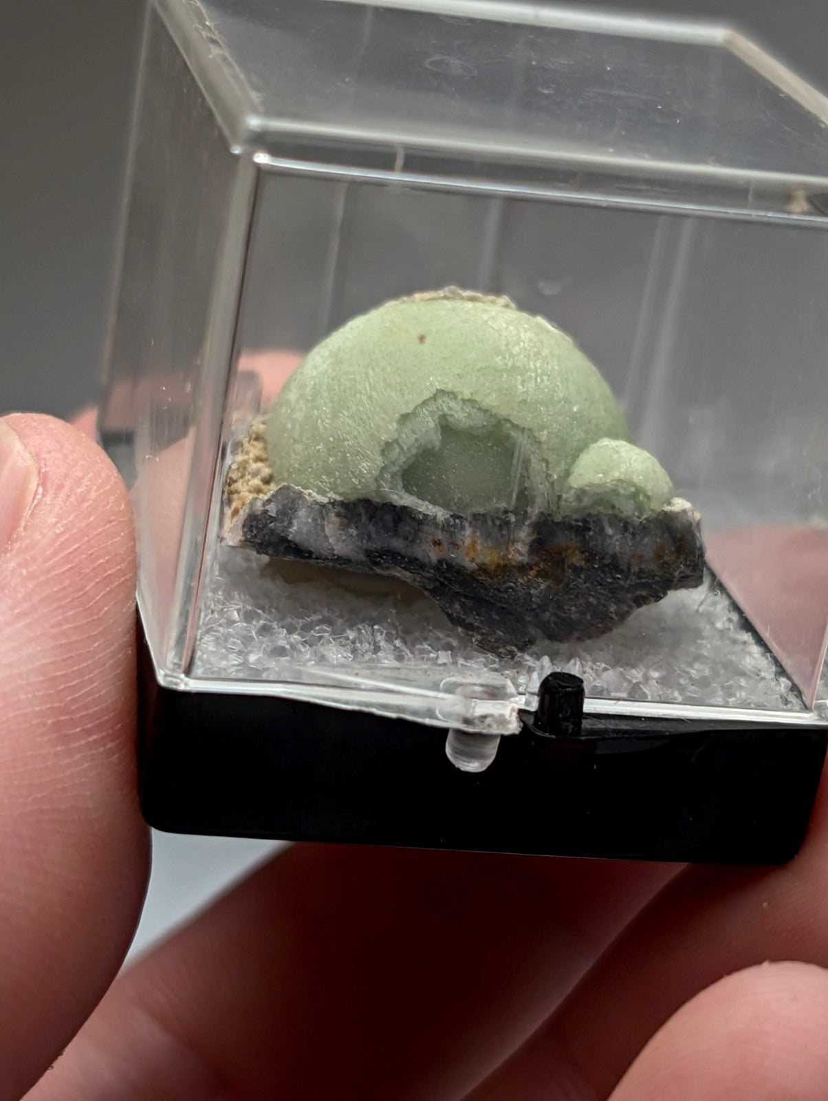Green wavellite mineral specimen dome shaped pale green rough texture on dark base rock in clear acrylic case from arkansas