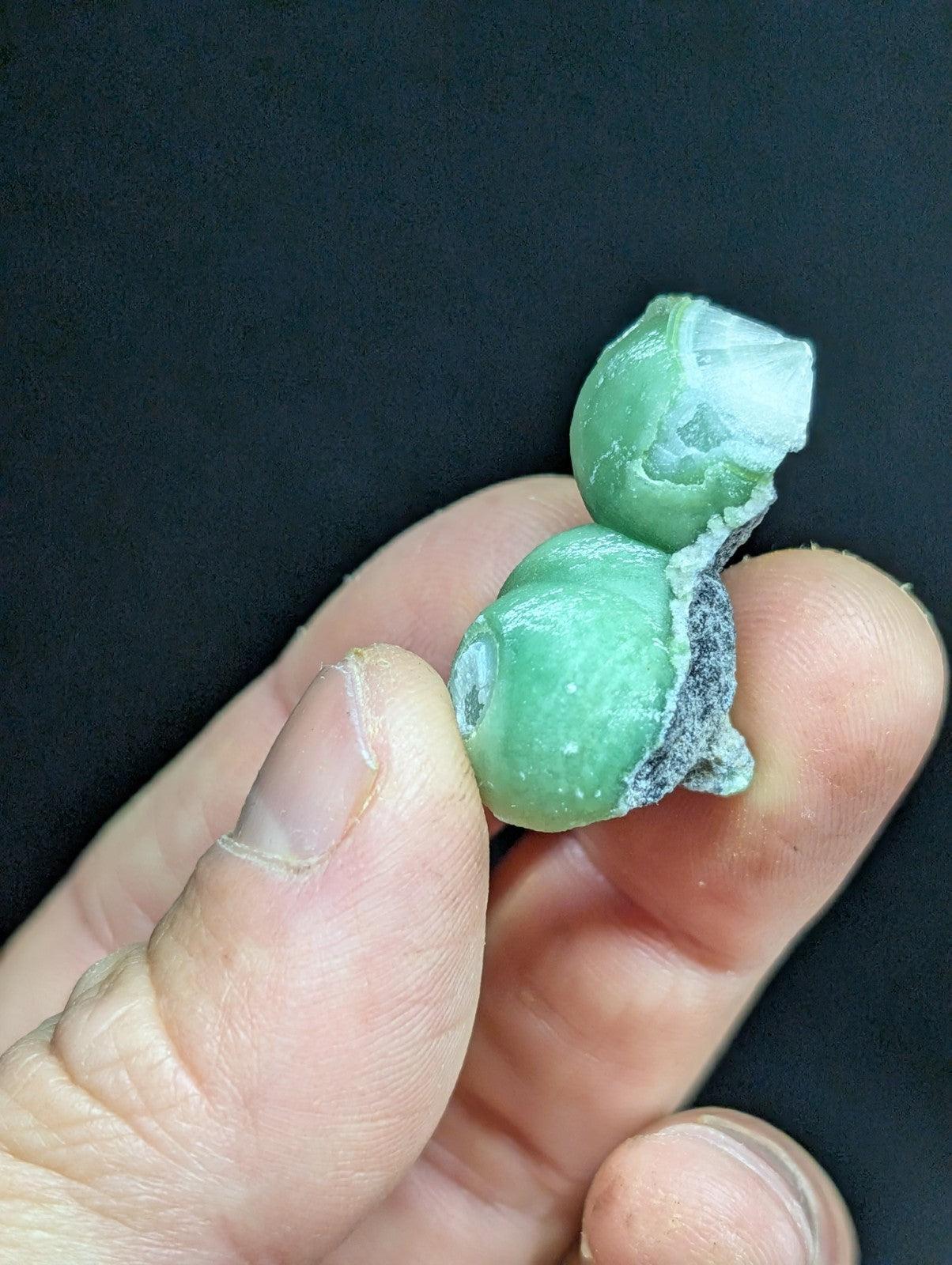 A pair of light green, translucent jade-like stones held in a hand.