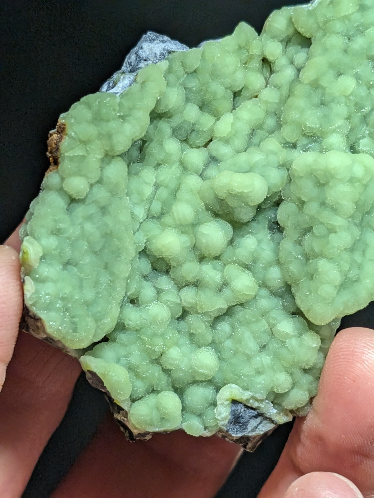 A vibrant green, bumpy mineral specimen with a crystalline texture and translucent quality.