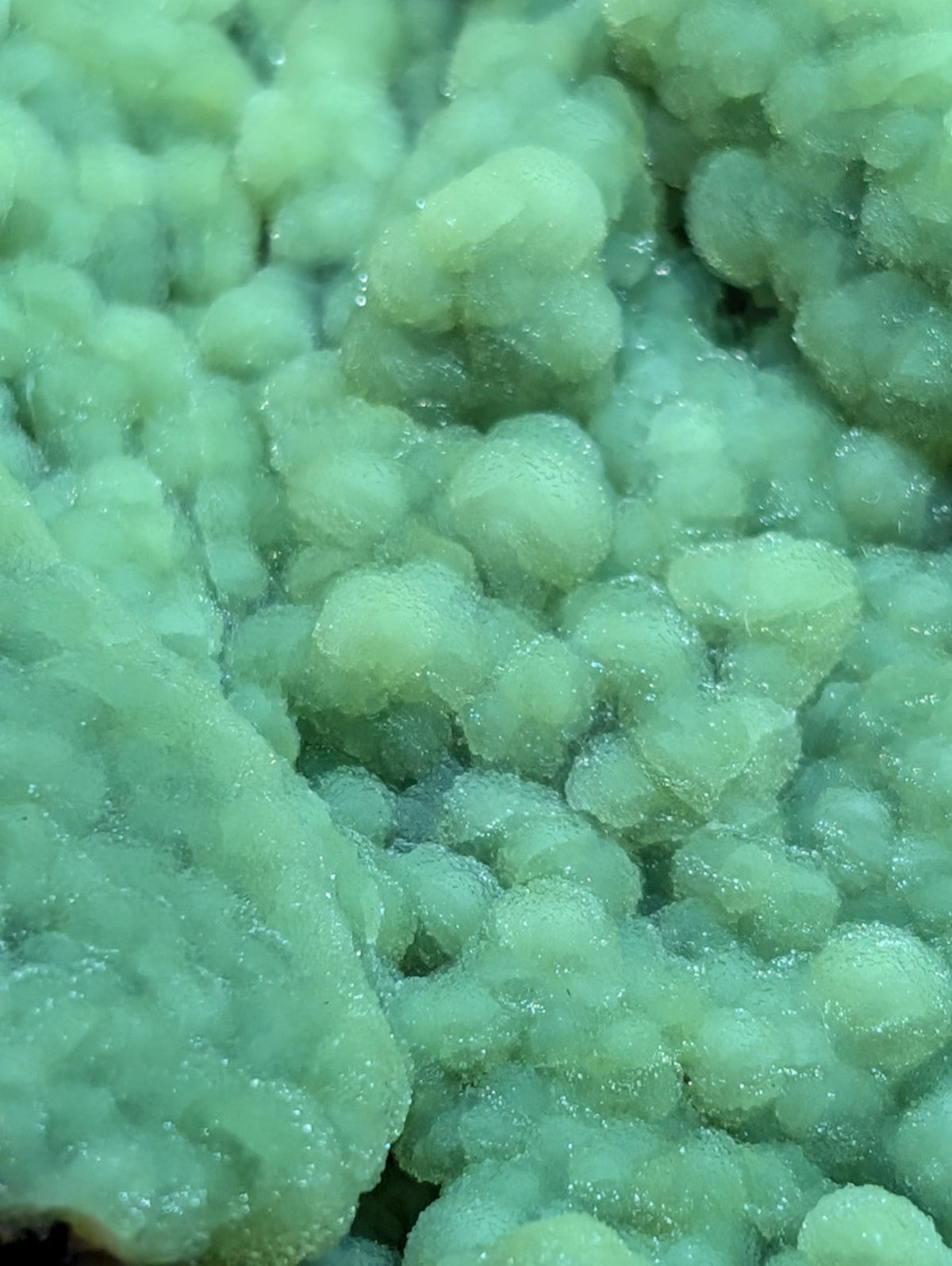 A cluster of translucent, pale green crystalline formations with a slightly rough and bubbly texture.