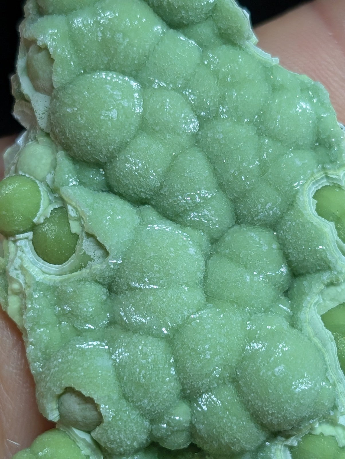 A vibrant green, bubbly mineral specimen with a textured, crystalline surface.