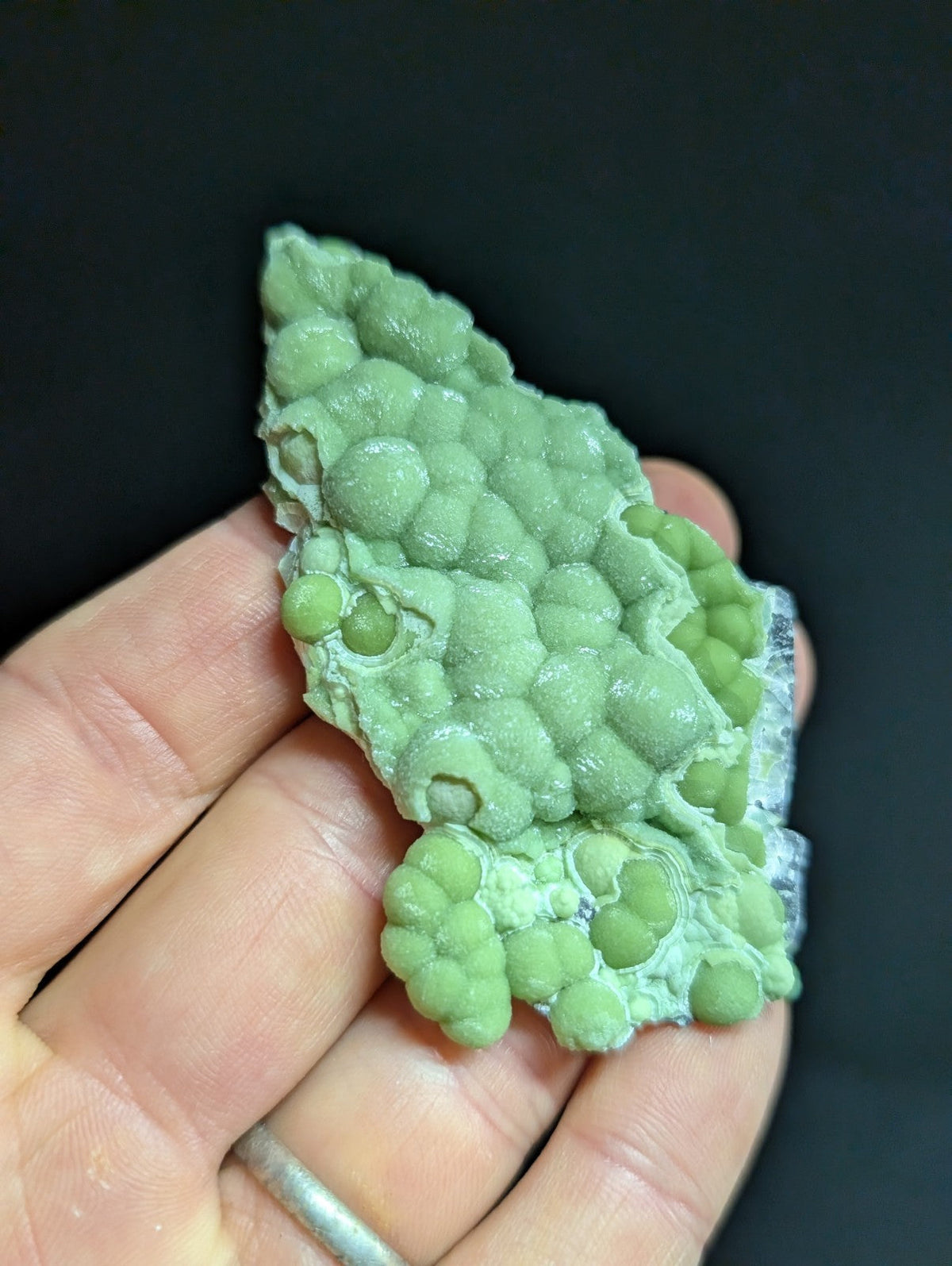 A pale green, textured mineral specimen with a bumpy, clustered surface and translucent edges.