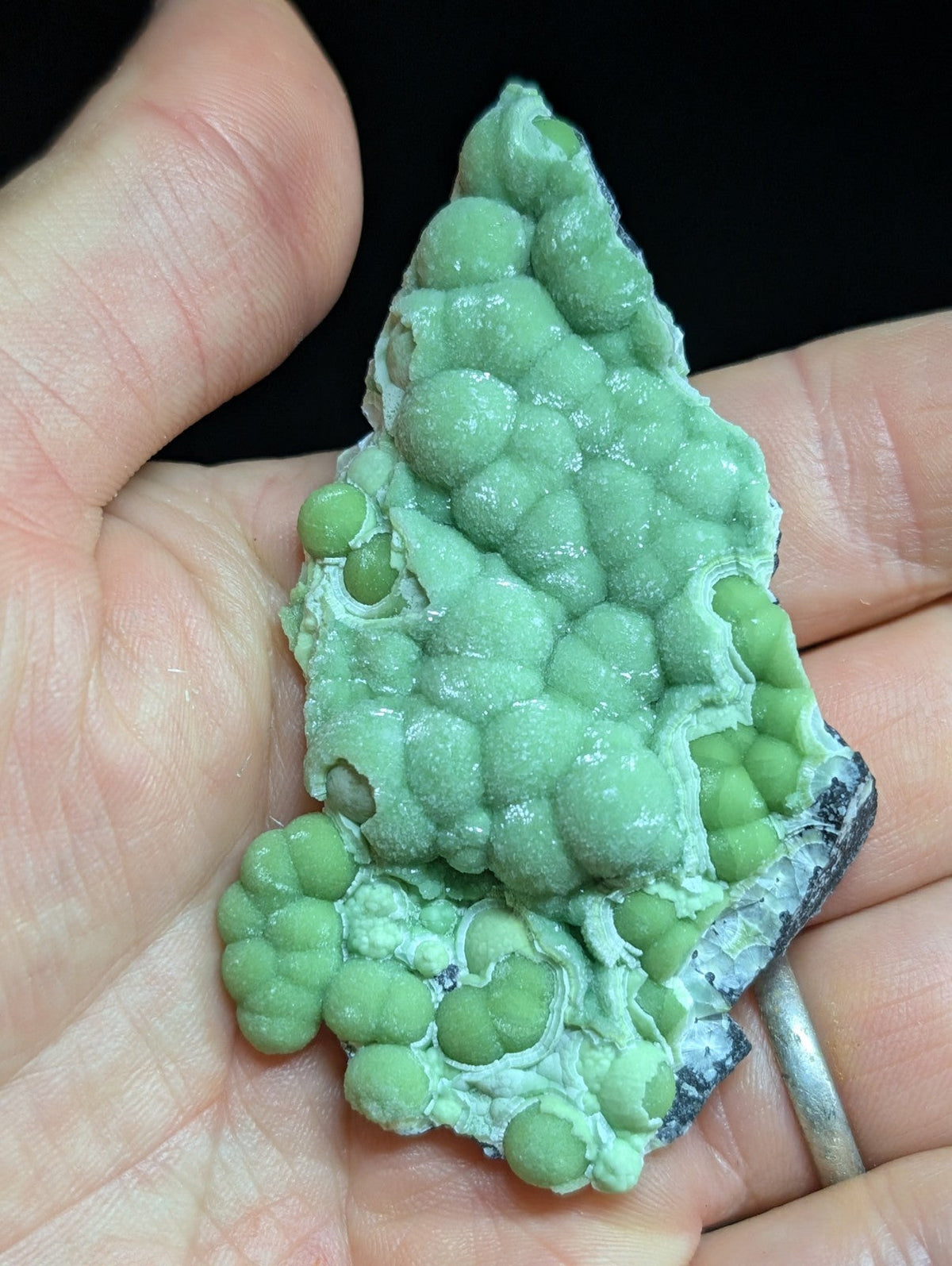 A vibrant green, bumpy mineral specimen with a textured surface and rounded nodules.