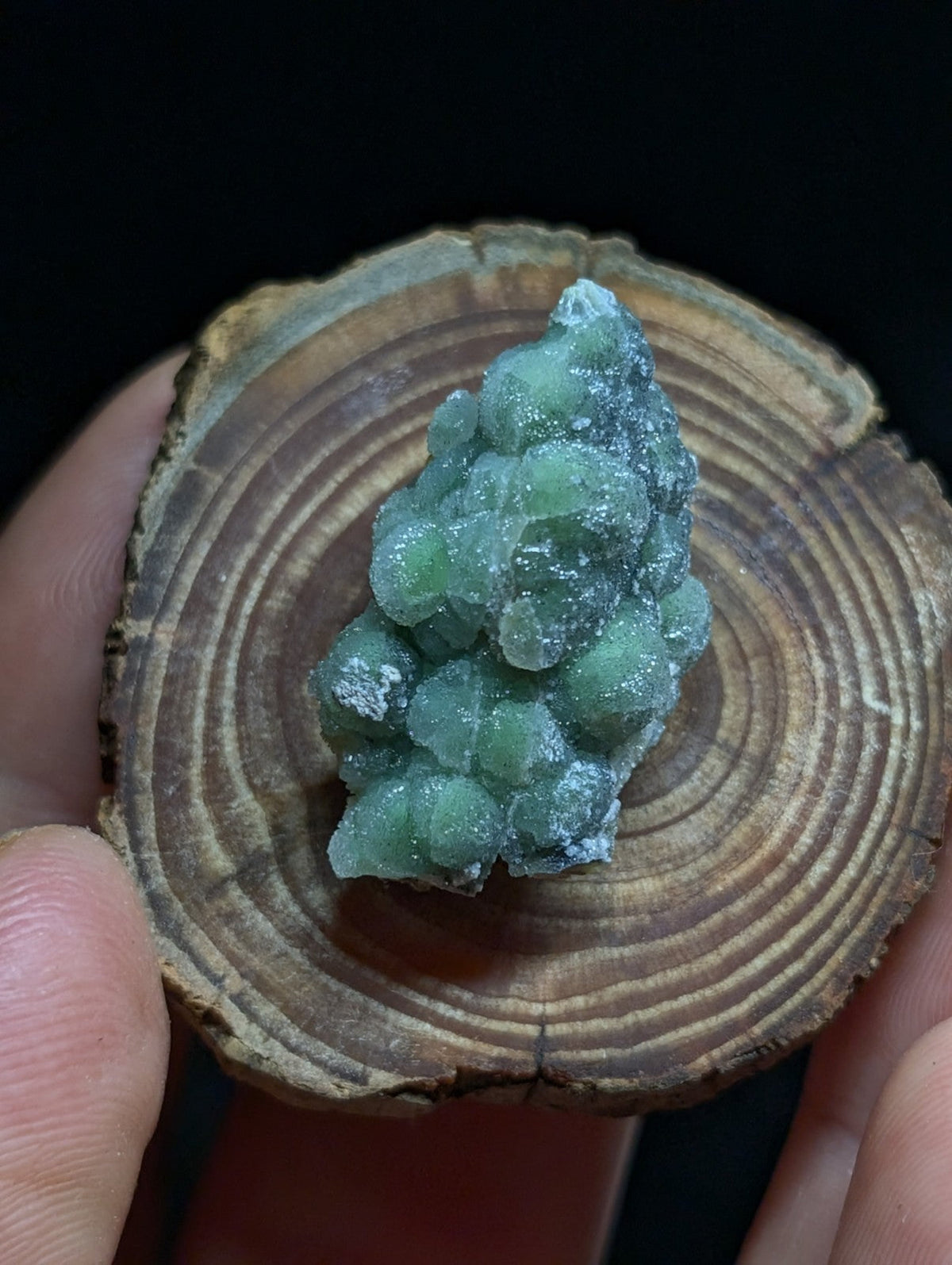 A translucent green mineral specimen with a clustered, rounded formation and crystalline texture.