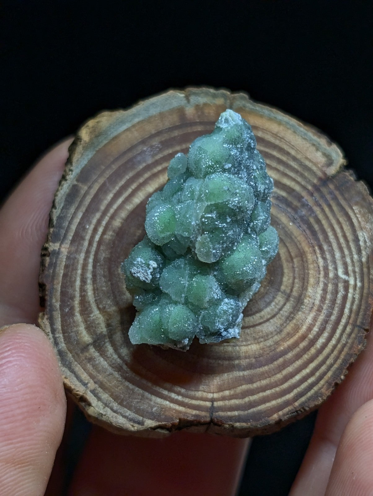 A translucent green mineral specimen with a clustered, rounded formation and crystalline texture.