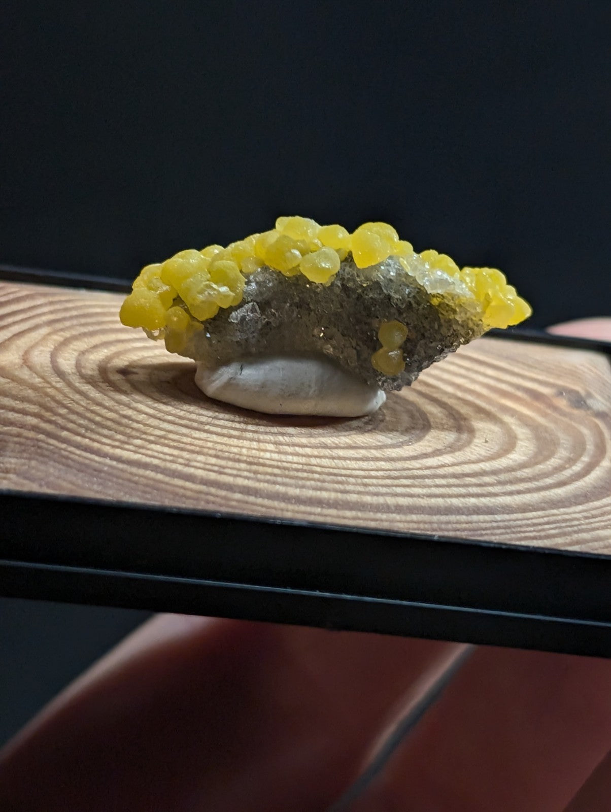 A vibrant yellow crystalline mineral specimen with a textured, earthy gray base.