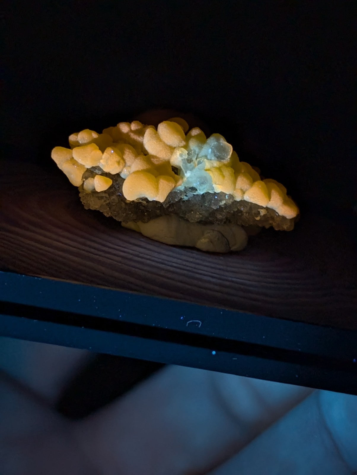 A striking yellow-orange mineral specimen with a cluster of translucent, crystalline formations and a darker base.