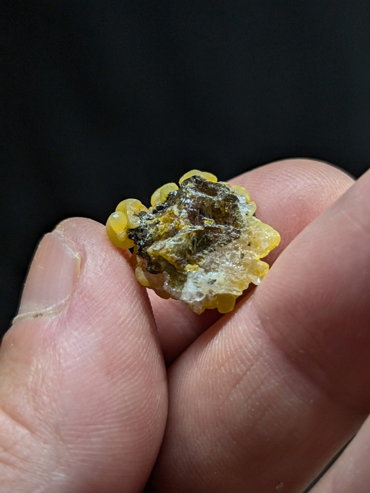 A yellow, translucent amber-like mineral specimen with a rough, irregular surface and dark inclusions.