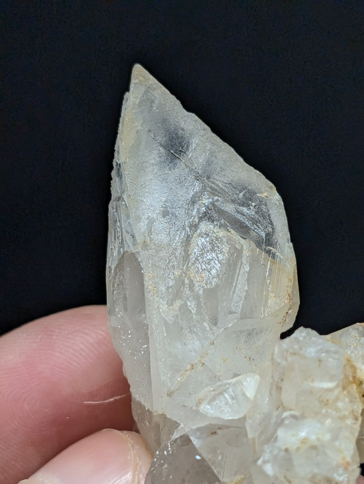 A translucent, clear quartz crystal cluster with a pointed tip and visible internal inclusions.