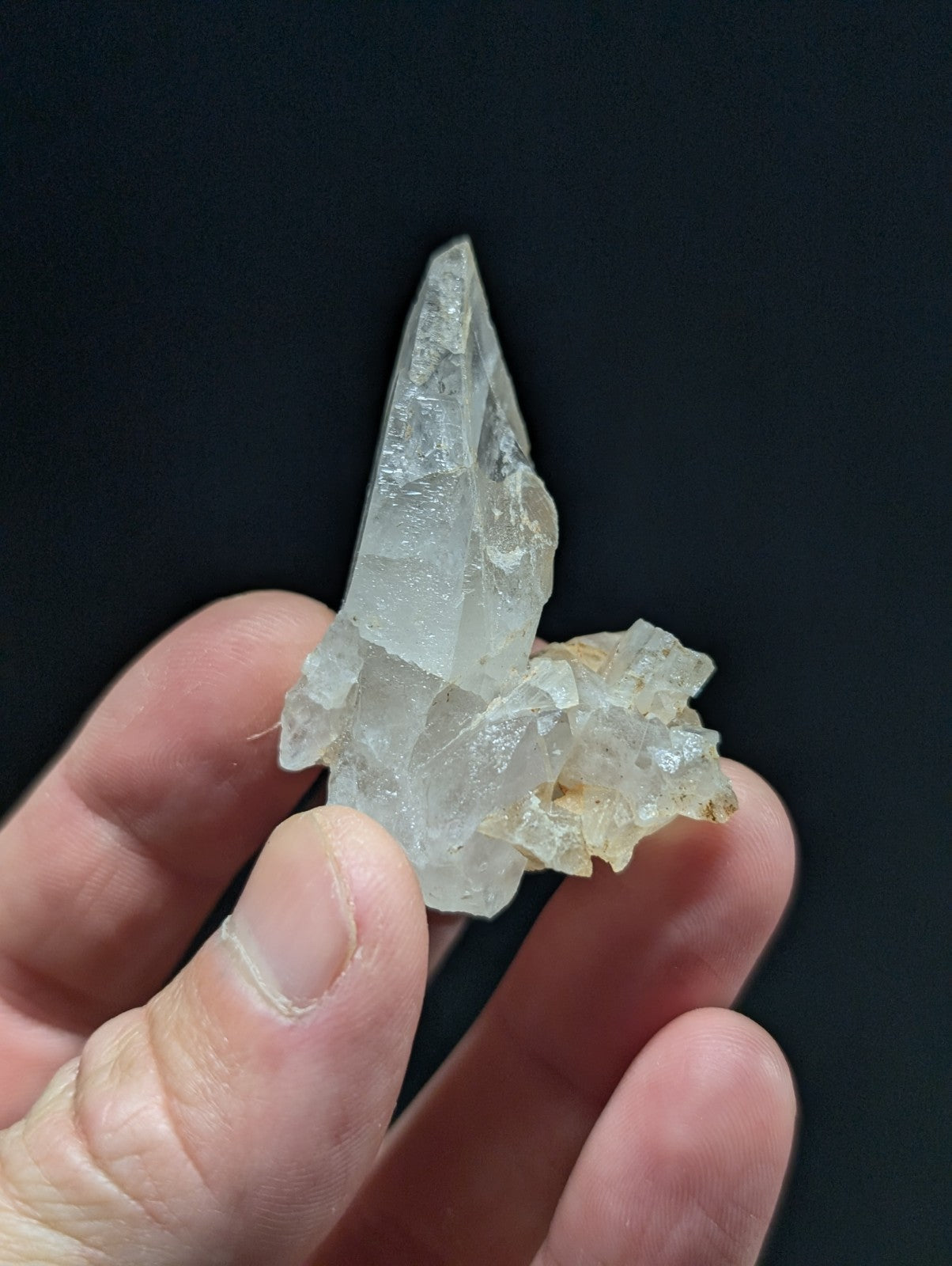 A translucent, clear quartz crystal cluster with a pointed tip and rougher base.