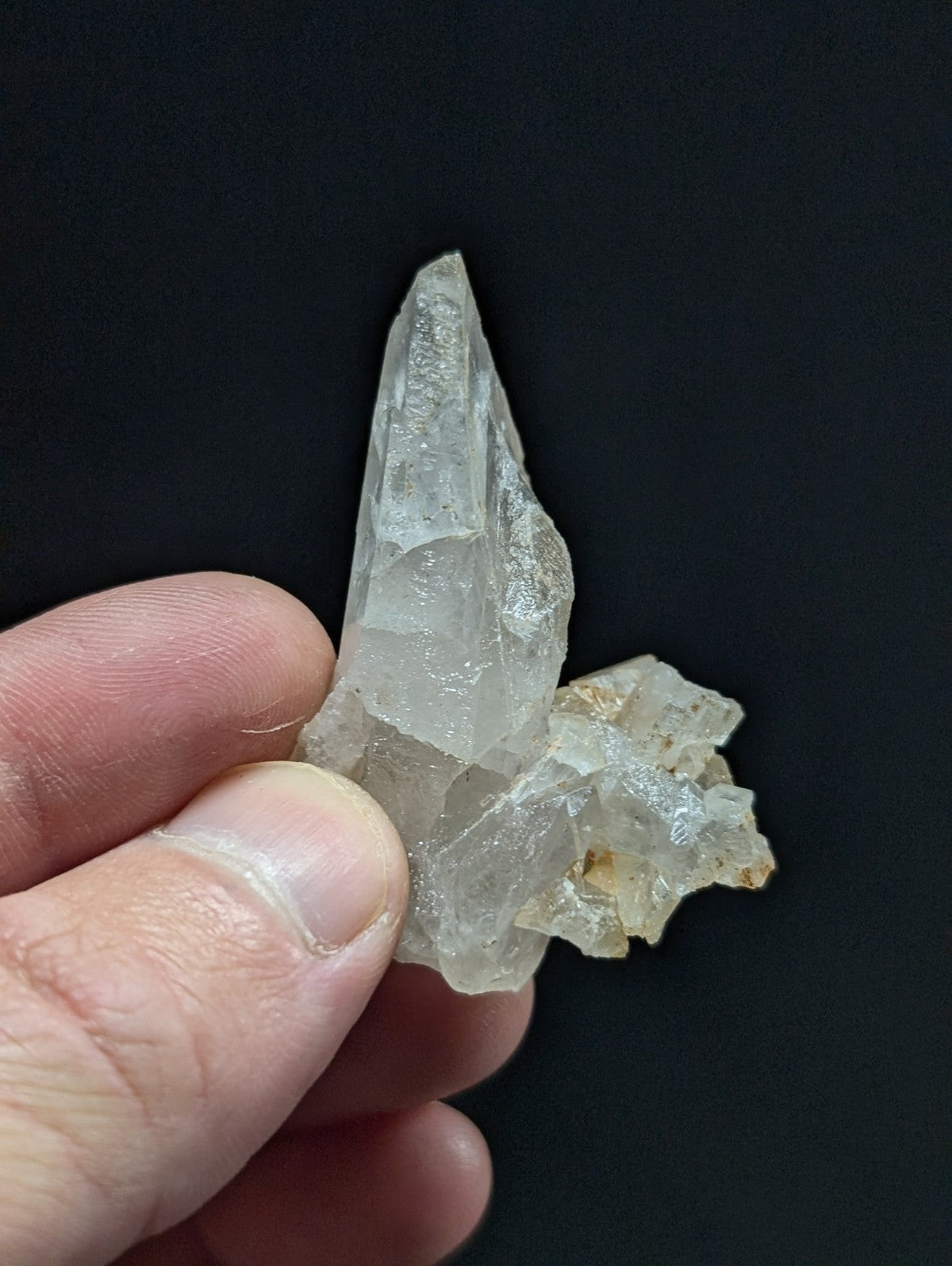 A translucent, clear quartz crystal cluster with a pointed tip and rougher base.