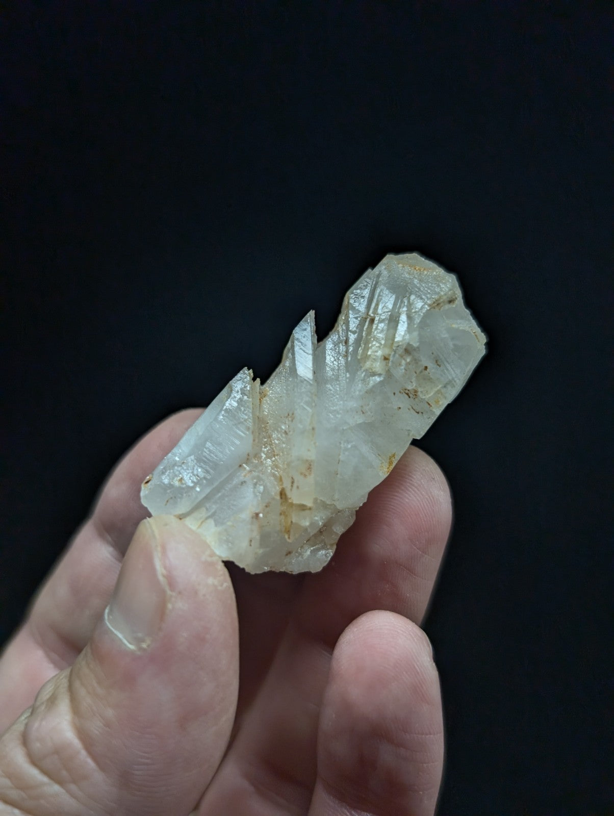 A translucent, pale quartz crystal cluster with sharp facets and subtle golden inclusions.