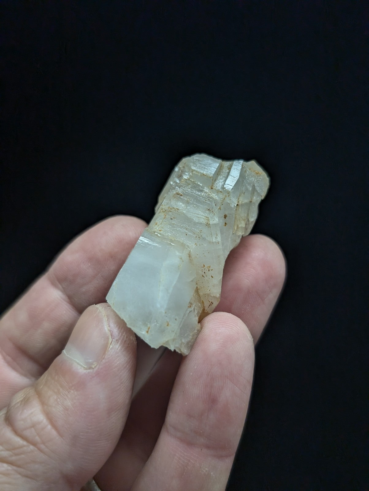 A translucent, pale greenish-white mineral specimen with visible crystalline facets and a rough, natural surface.