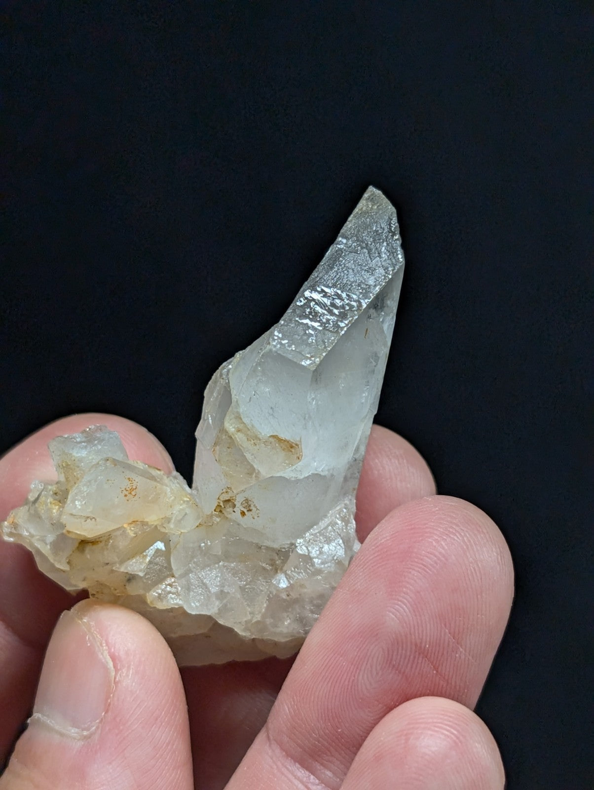A translucent, pale quartz crystal cluster with a pointed tip and rougher base.