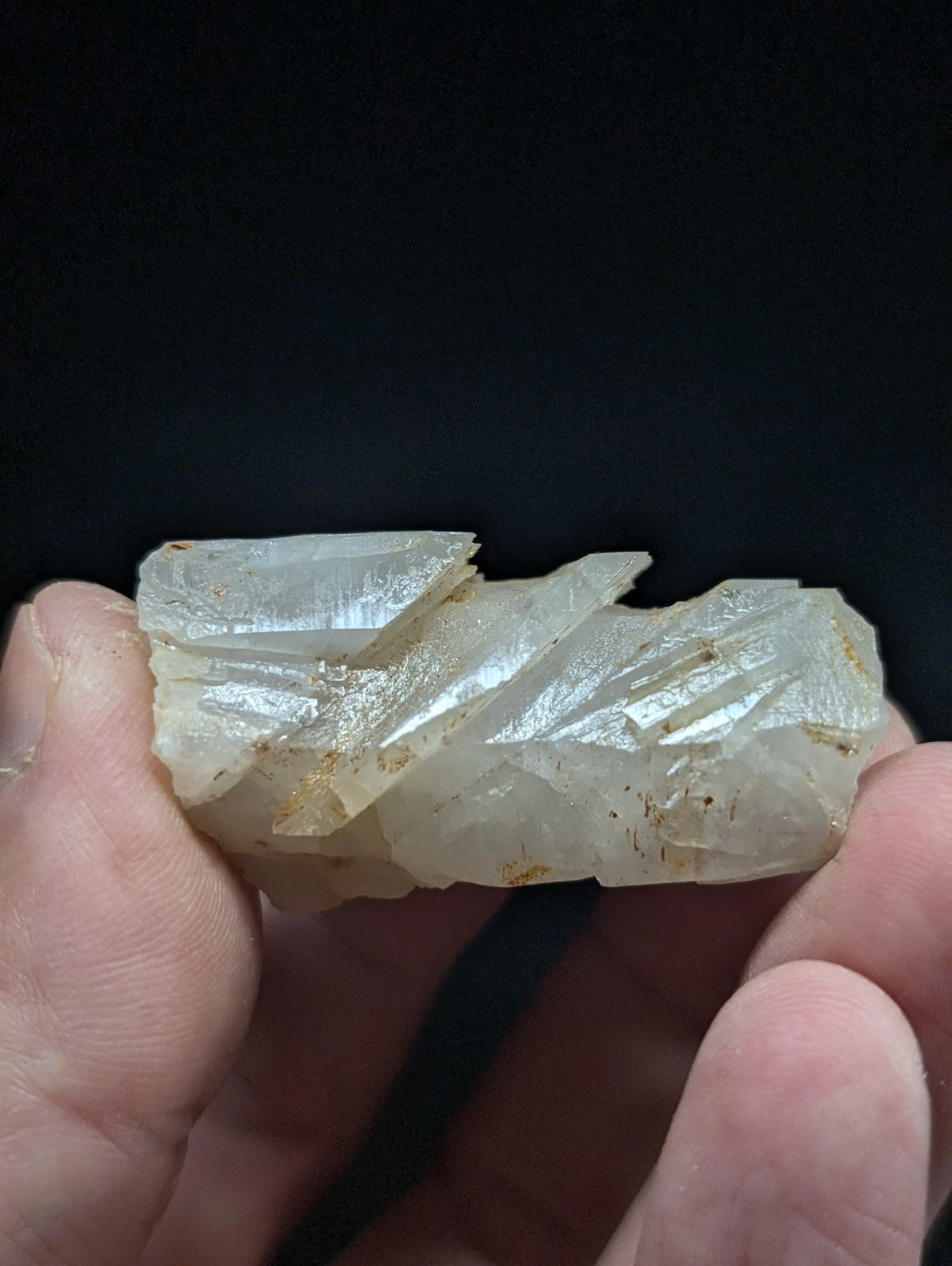 A translucent, pale white mineral specimen with jagged edges and subtle golden inclusions.