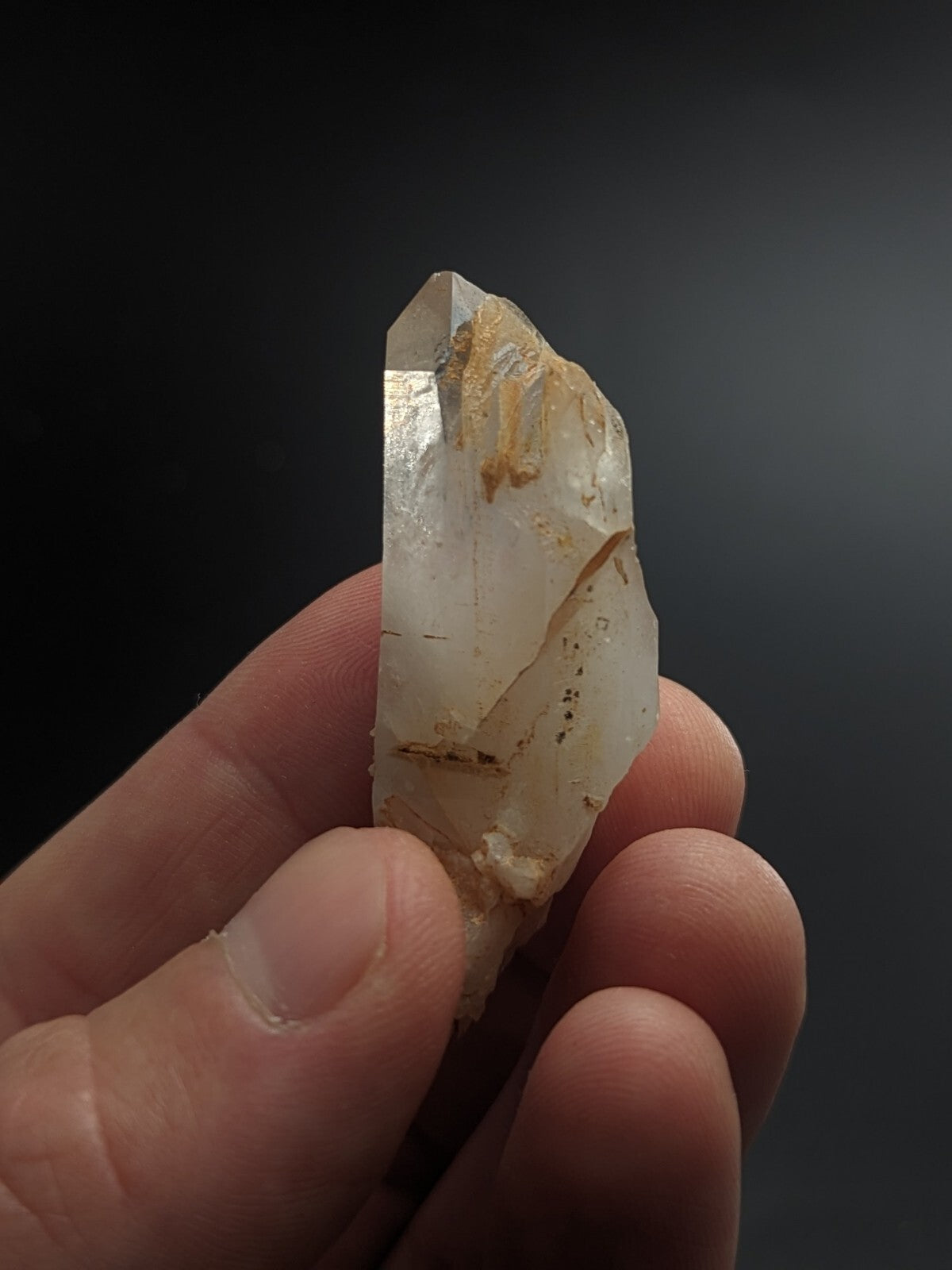 A translucent, pale quartz crystal with natural inclusions and a pointed tip.