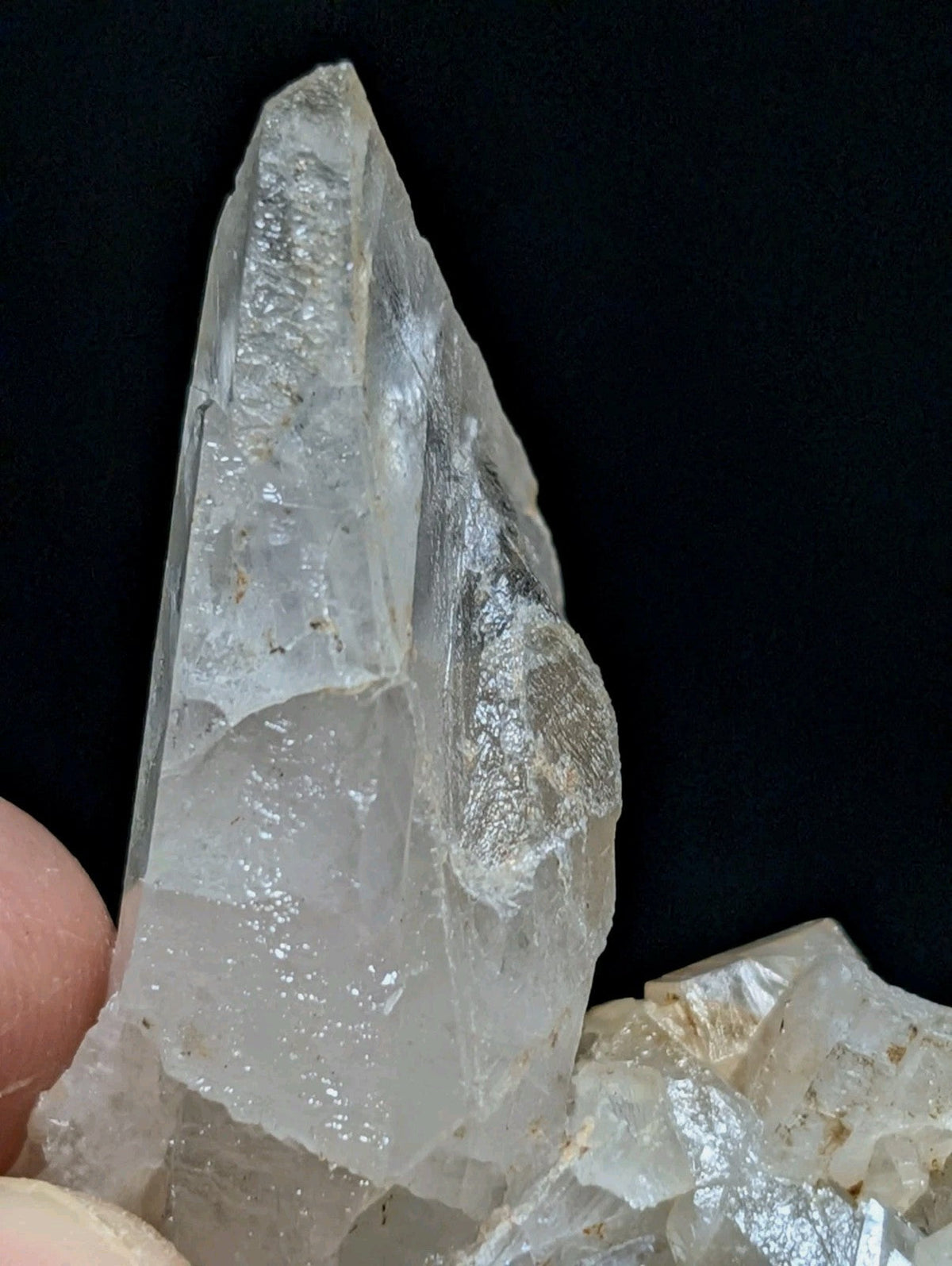 A translucent, clear quartz crystal with a pointed tip and visible internal inclusions.