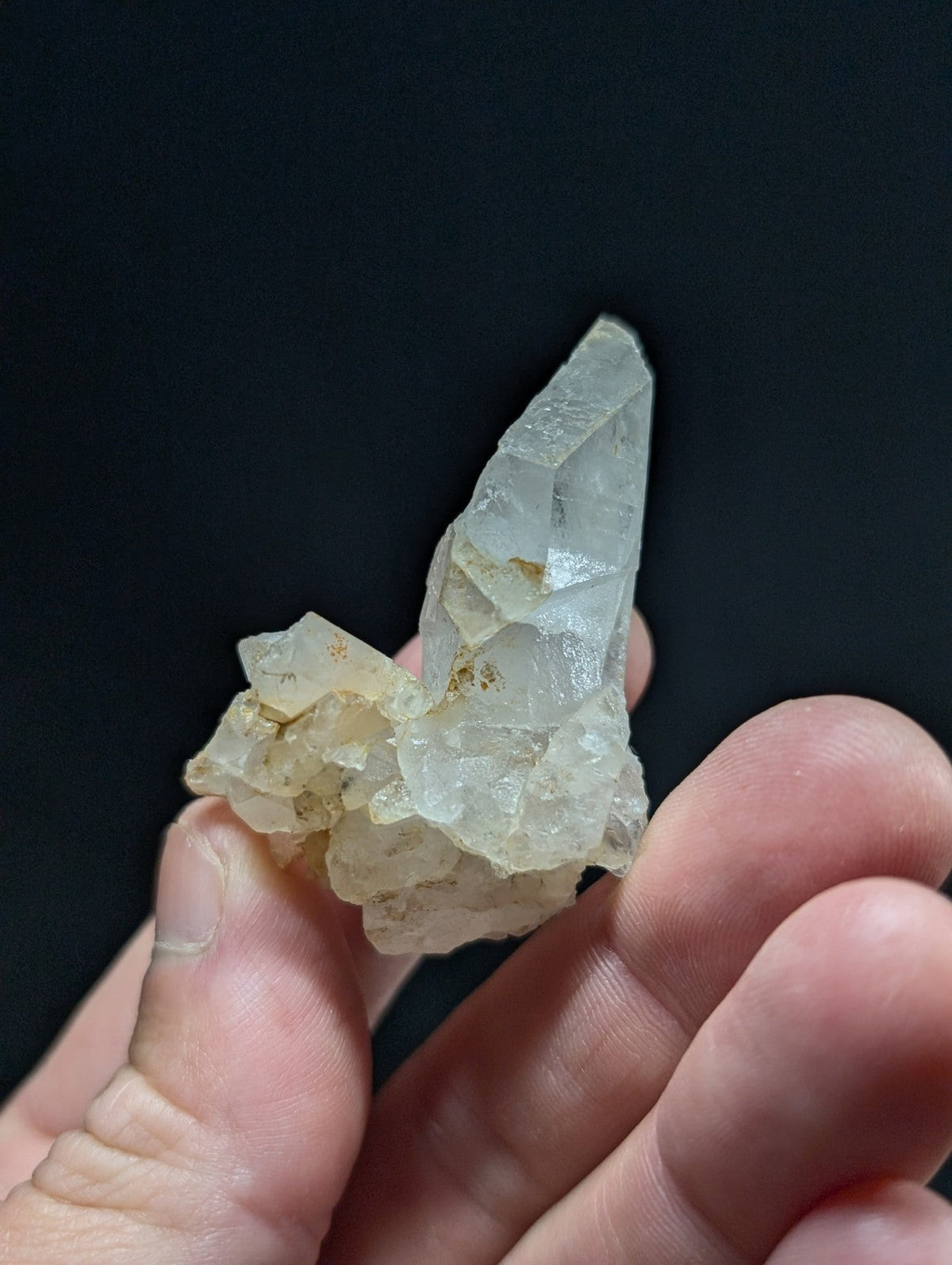 A translucent, pale quartz crystal cluster with sharp geometric facets and subtle golden inclusions.
